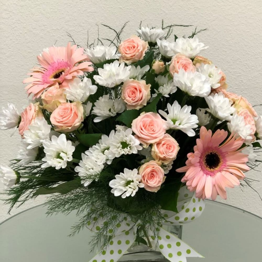 Pink gerbera daisies and pale roses with white daisies in a glass vase