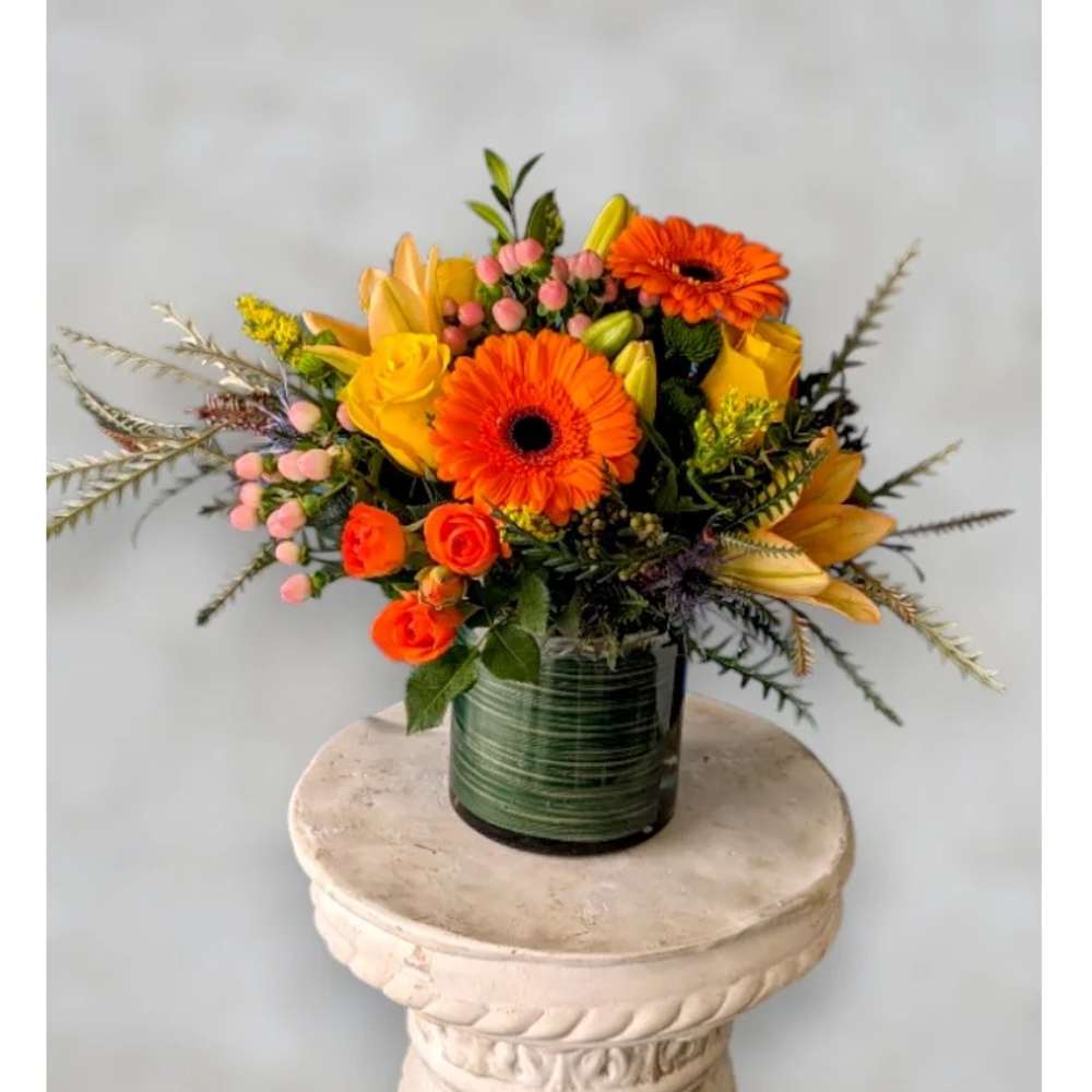 Orange and yellow mixed flower arrangement in a glass vase