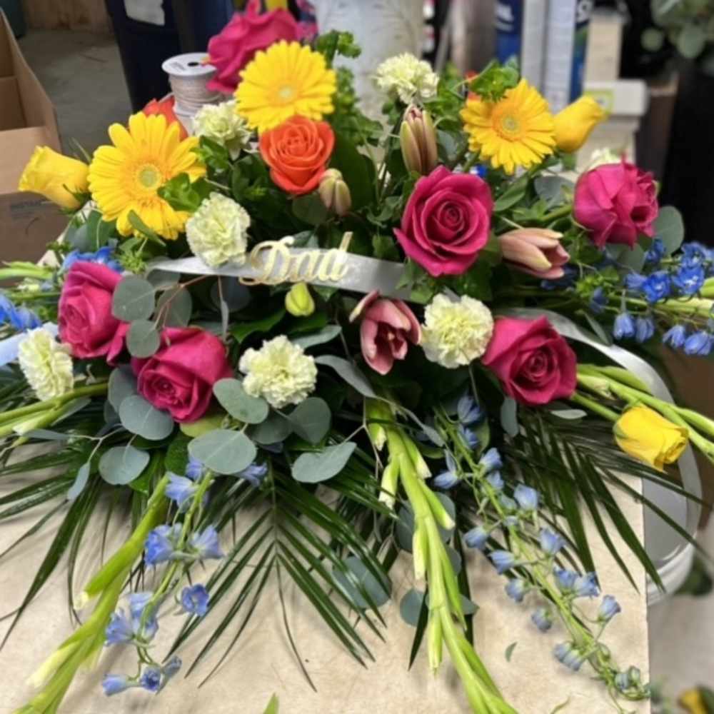 Colorful floral arrangement with roses, daisies, and blue accents