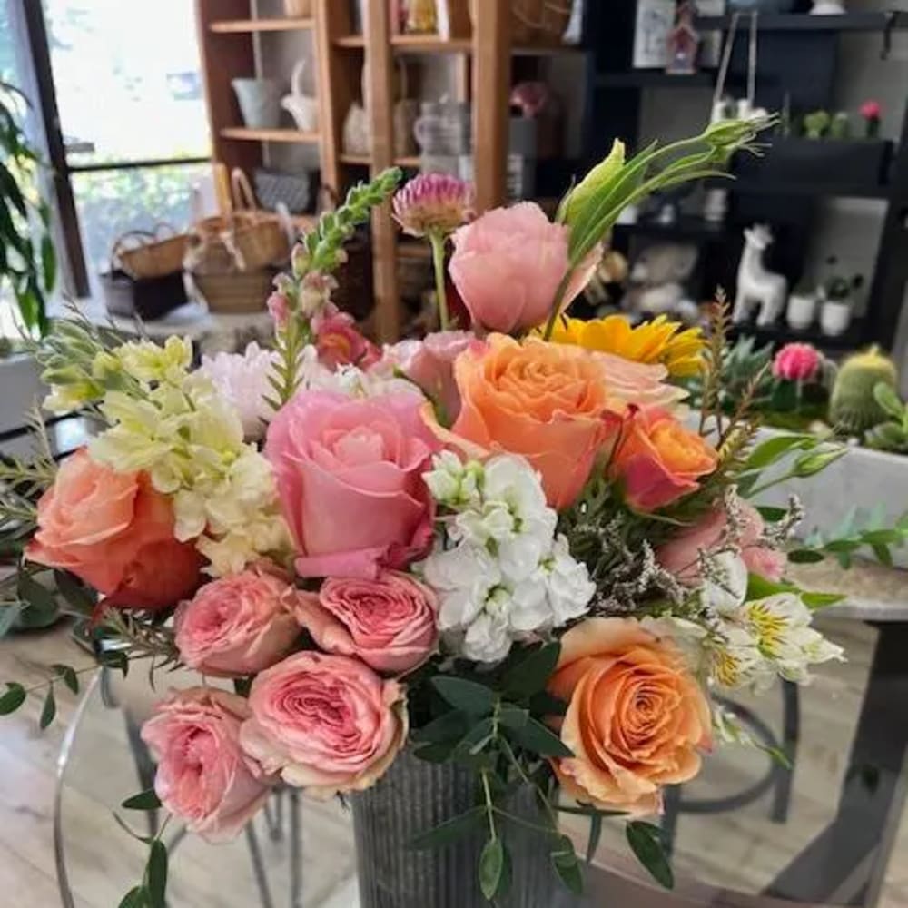 Mixed pink, peach, and white flower arrangement in a gray vase