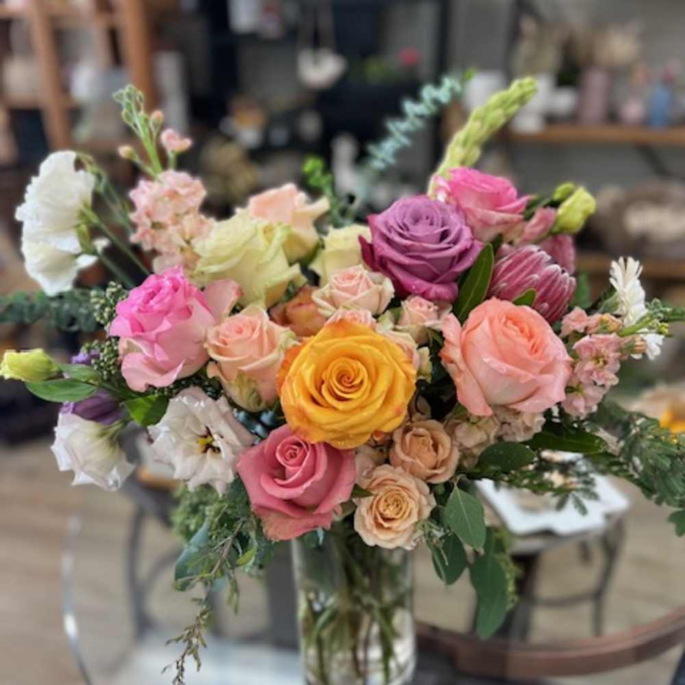 Mixed bouquet of roses and other blooms in a glass vase