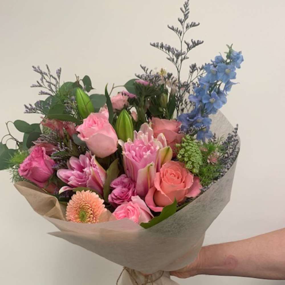 Hand-tied bouquet of pink and blue flowers wrapped in paper