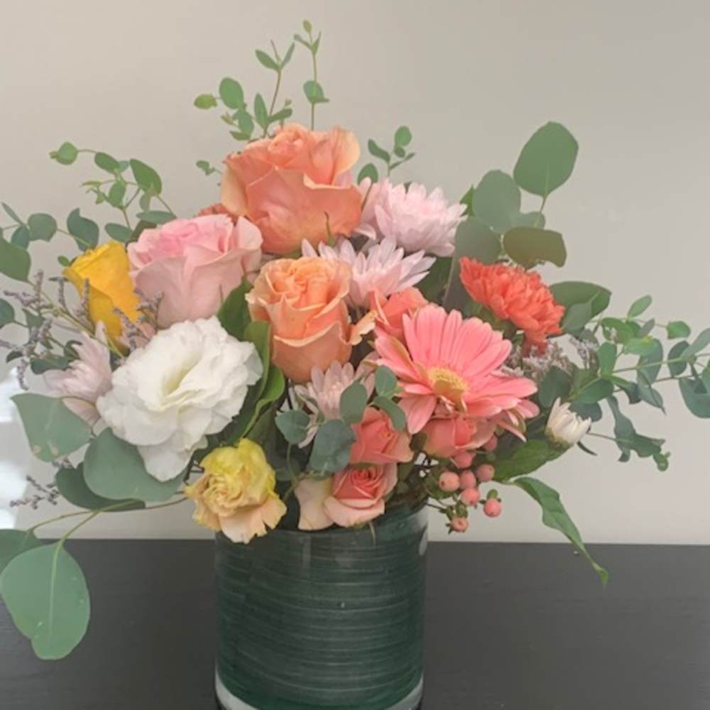Mixed bouquet of pastel flowers in a green glass vase