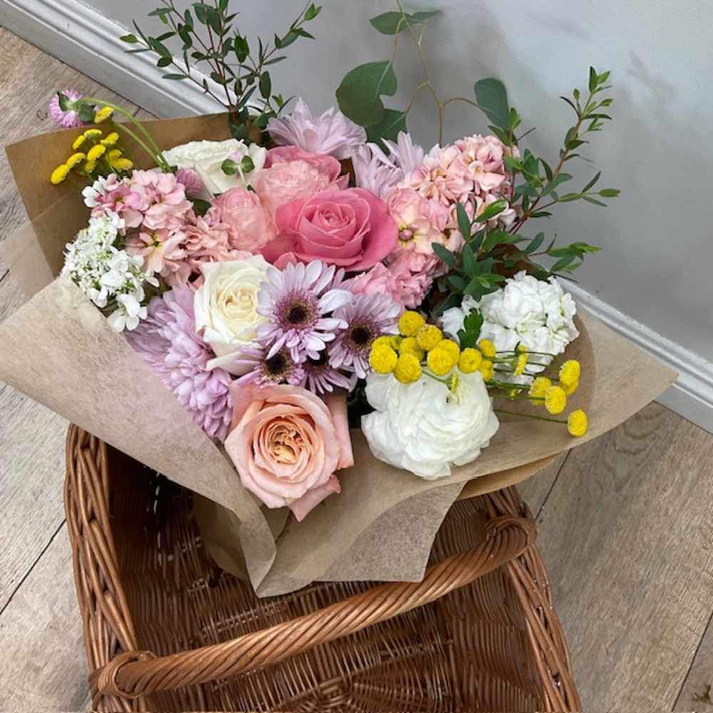 Bouquet of pink, white, and yellow flowers wrapped in brown paper