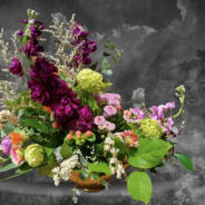 Mixed bouquet with purple and pink flowers in a low gold bowl