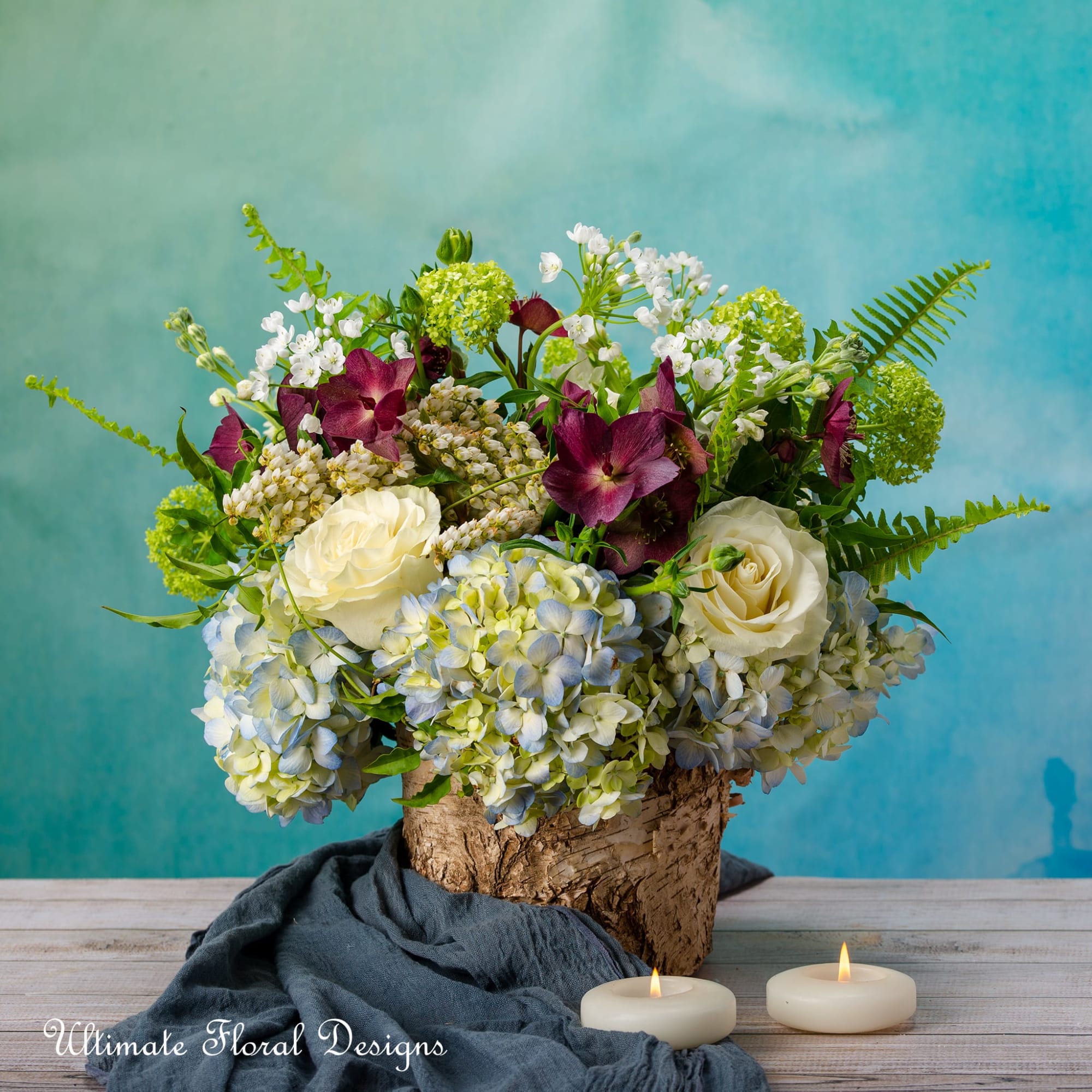 Floral arrangement in a birch bark container with candles in front