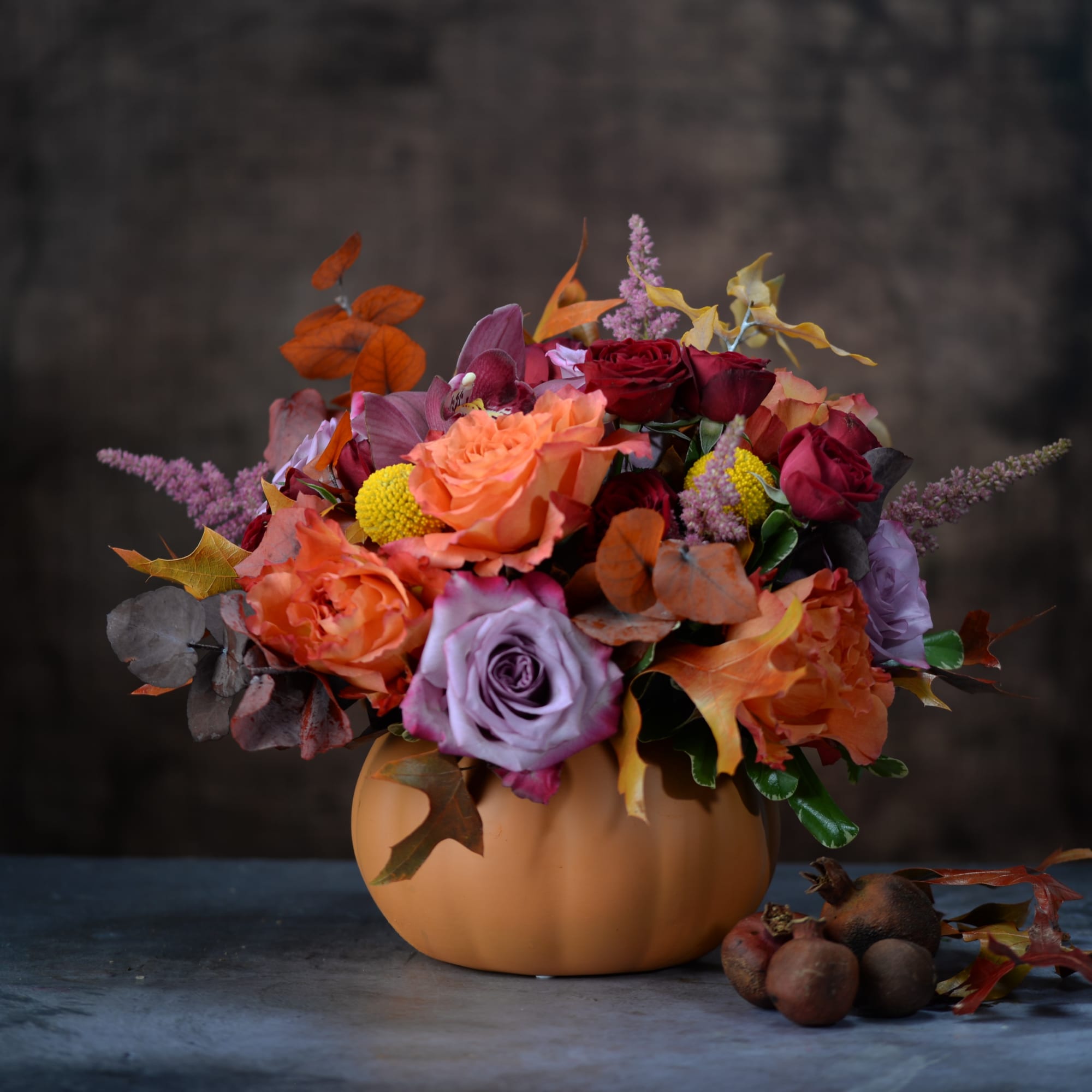 Autumn bouquet in a pumpkin-shaped vase with roses and mixed blooms