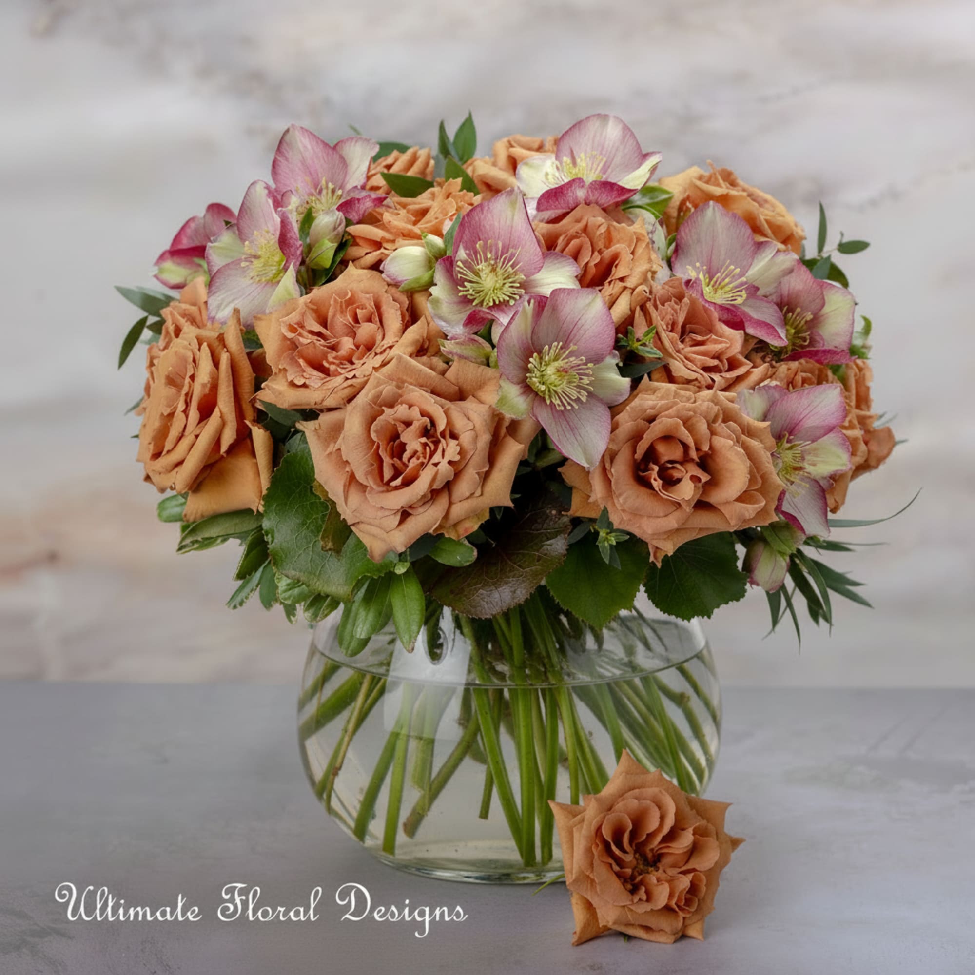Peach roses and pink-white hellebore in a clear glass vase