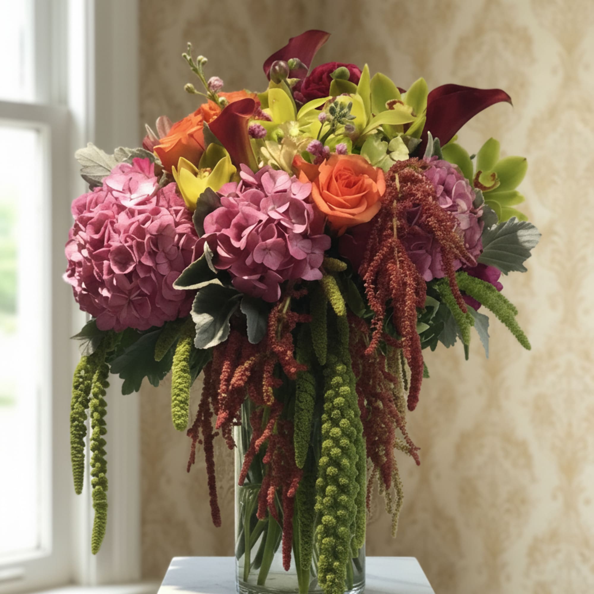Bouquet of pink hydrangeas, orange roses, and calla lilies in a glass vase