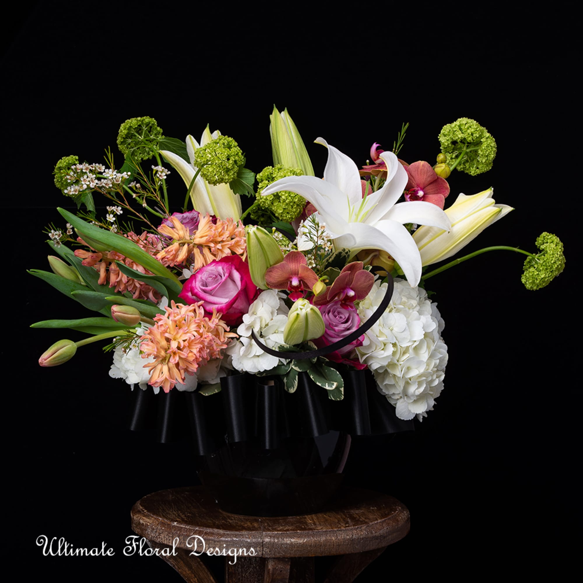 Mixed floral arrangement with white lilies, hydrangeas, and pink roses in a black container