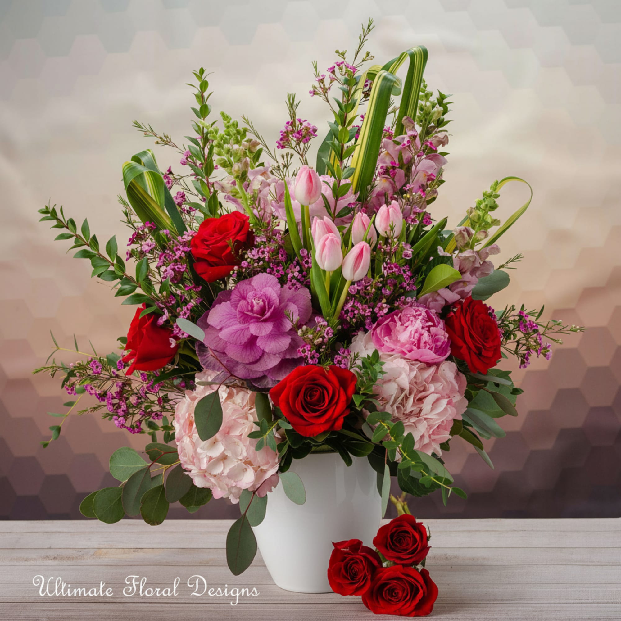 Mixed bouquet of red roses, pink tulips, and hydrangeas in a white vase