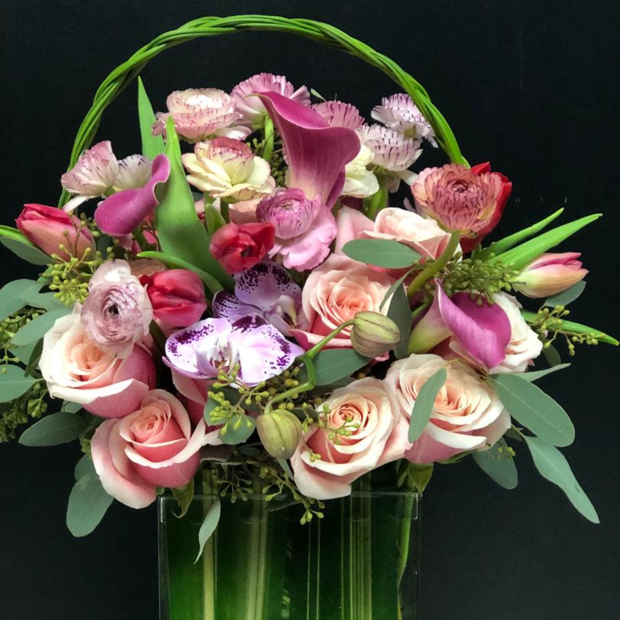 Pink and white floral arrangement in a tall glass vase with a green handle