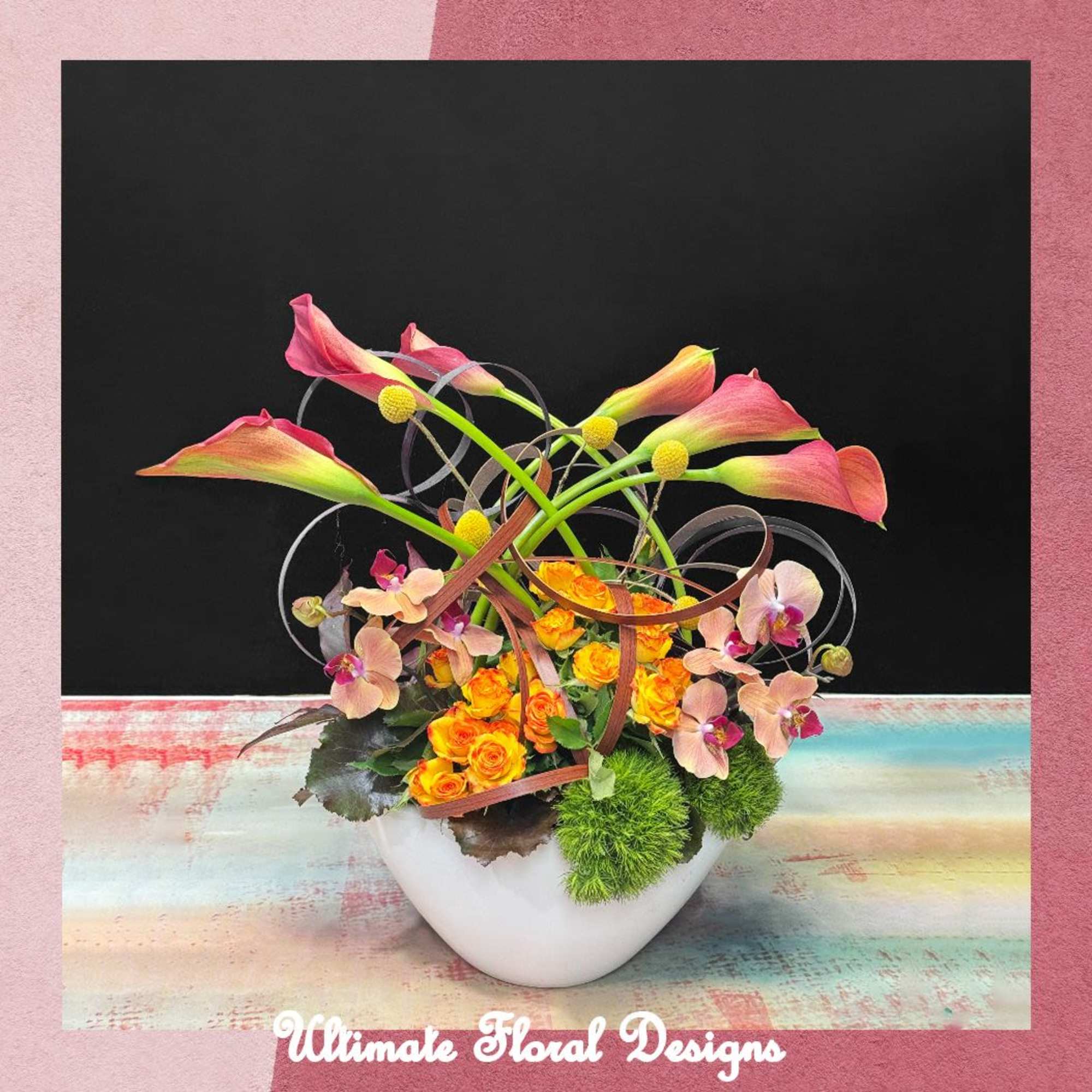 Modern floral arrangement with pink calla lilies, orange roses, and orchids in a white vase