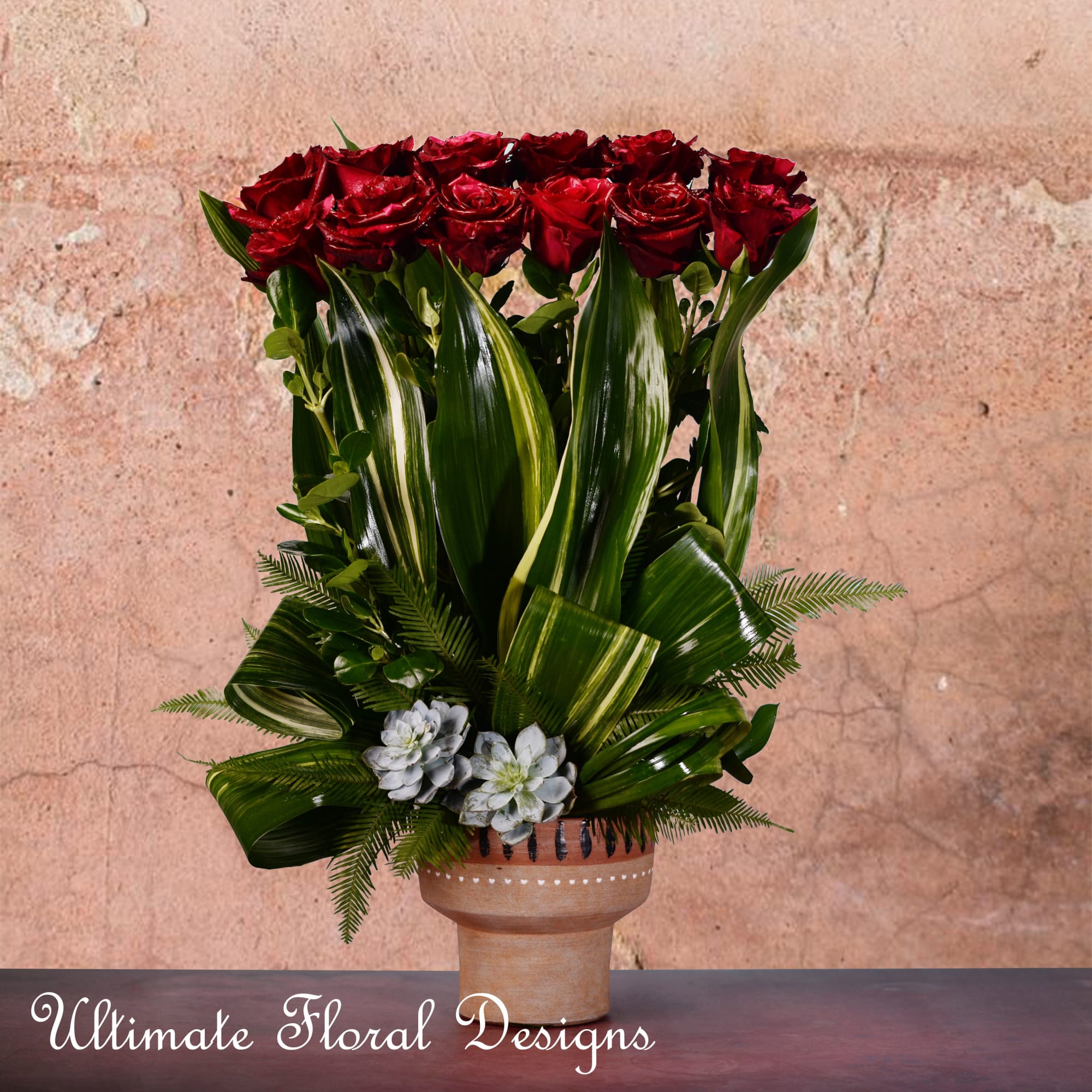 Tall arrangement of red roses and green foliage in a terracotta vase