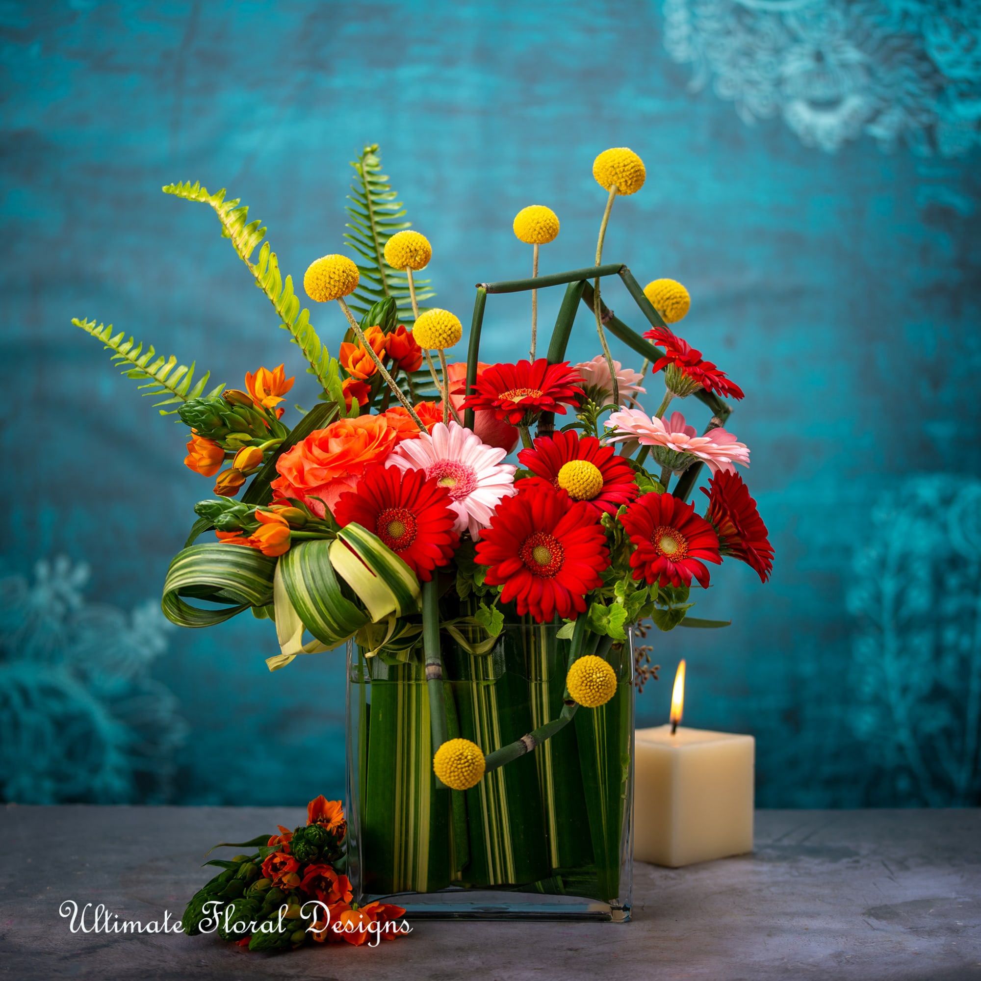 Mixed bouquet in a glass vase with a lit candle beside it