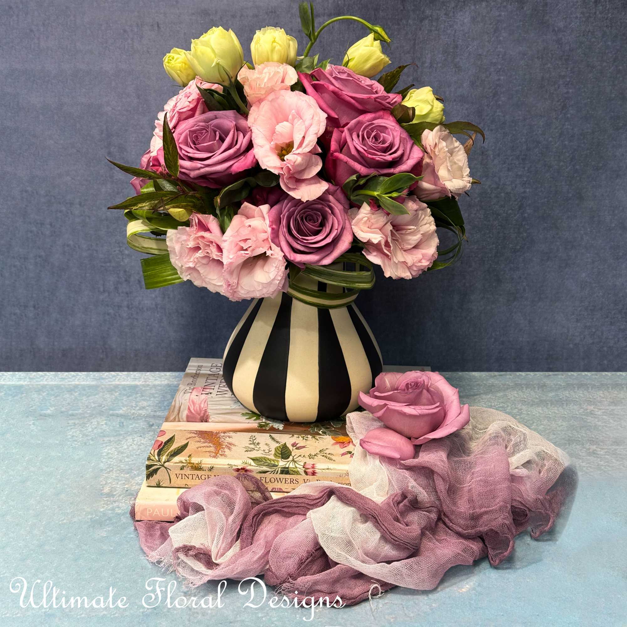 Bouquet of pink and purple roses with pale pink blooms in a striped vase
