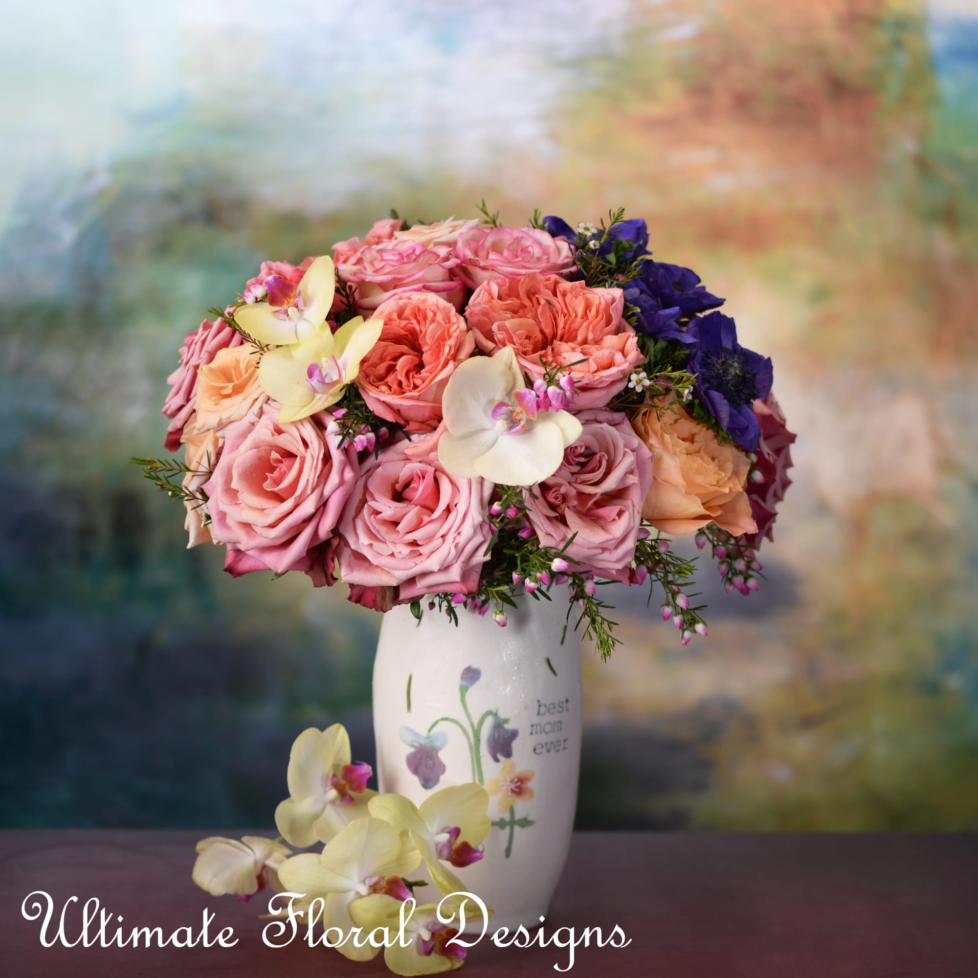 Pink and peach roses with orchids in a white vase