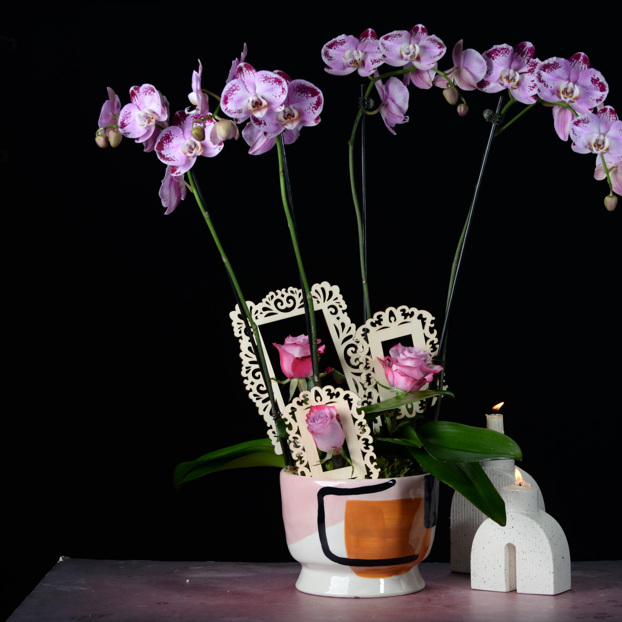 Pink orchids and roses arranged in a painted ceramic pot