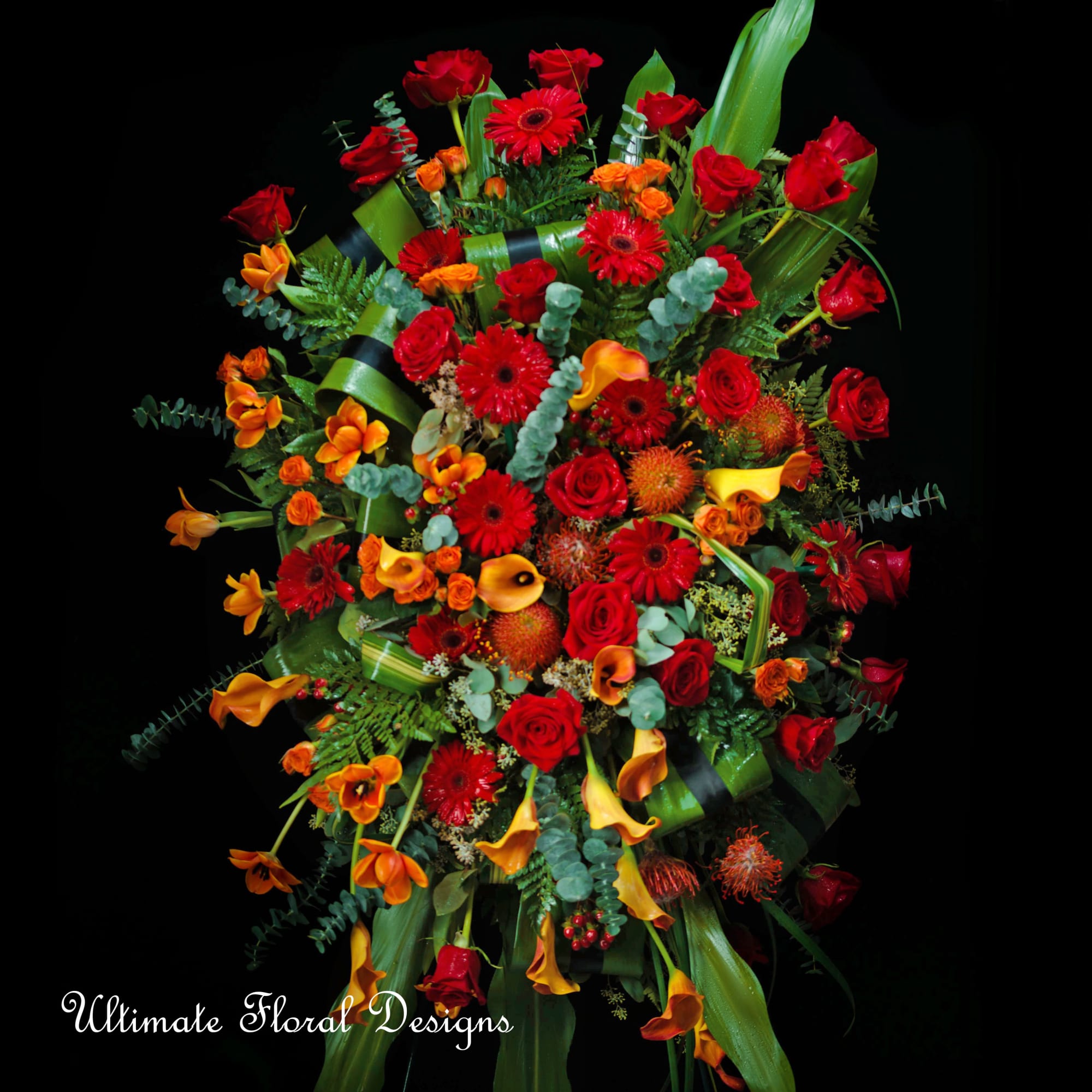 Large bouquet of red and orange flowers with green foliage on a black background