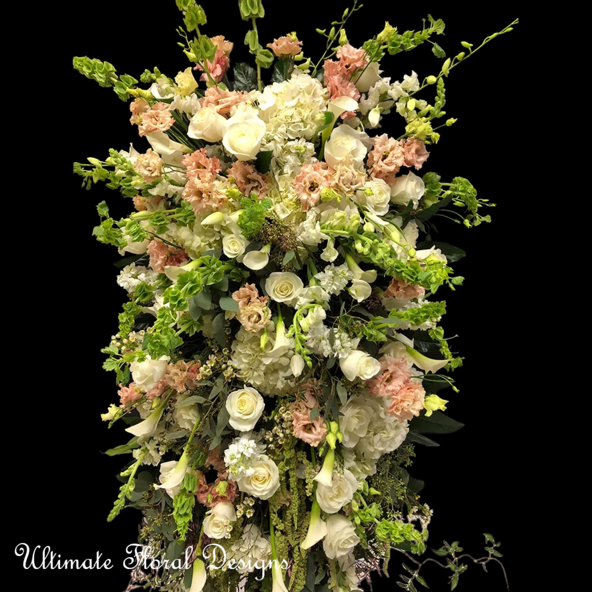 Tall floral arrangement with white roses, calla lilies, and pale pink blooms