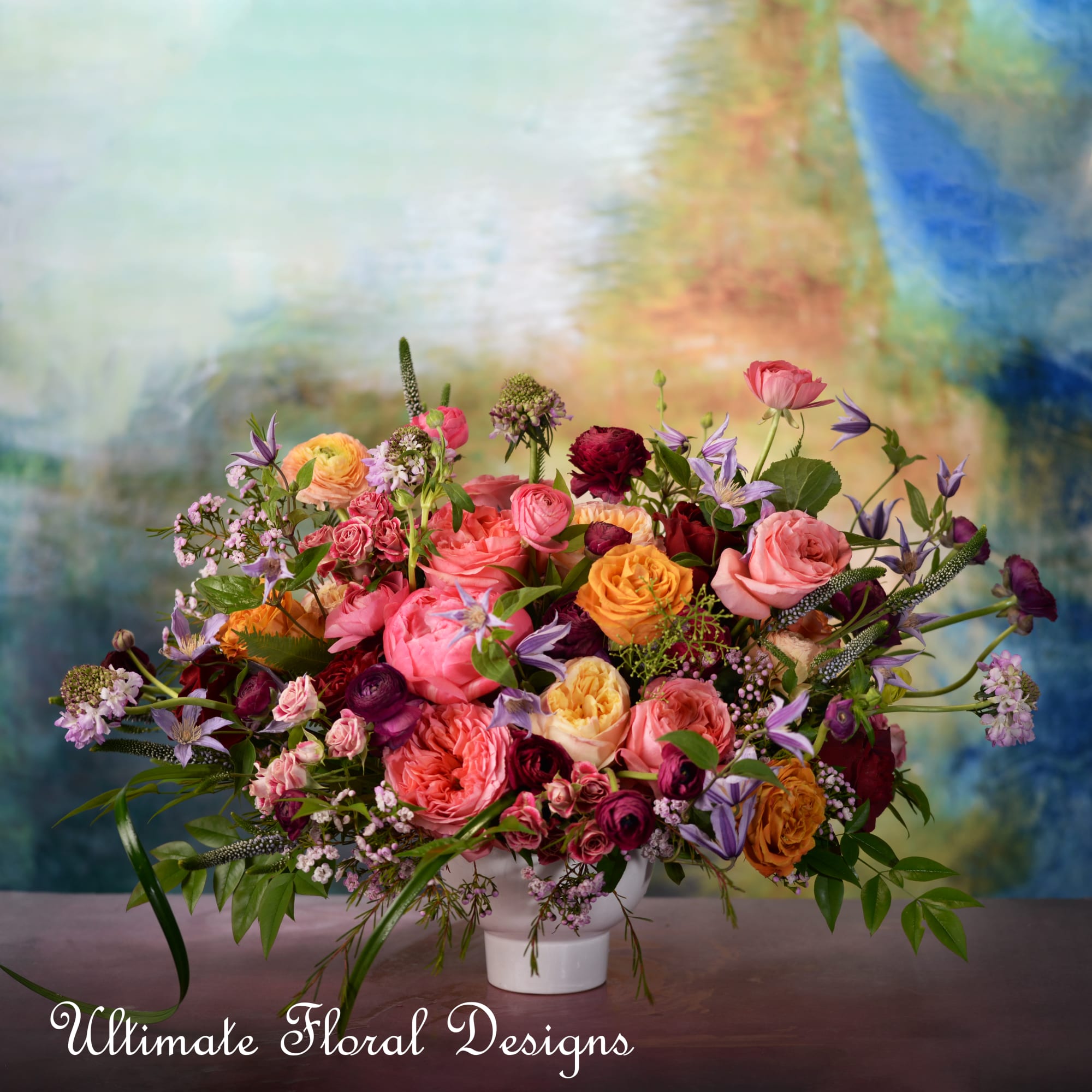 Mixed pink, peach, and purple flowers arranged in a white vase