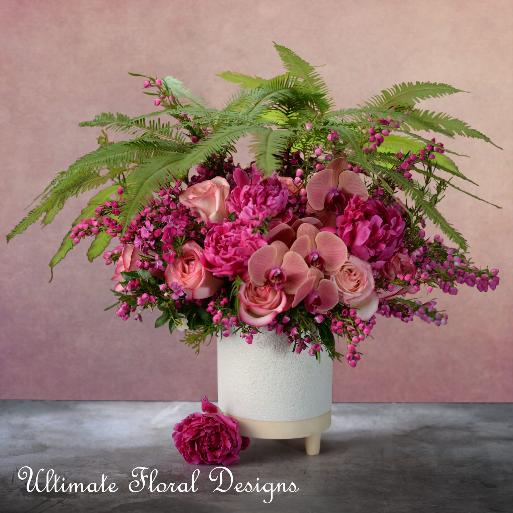 Pink floral arrangement in a white vase with orchids and roses