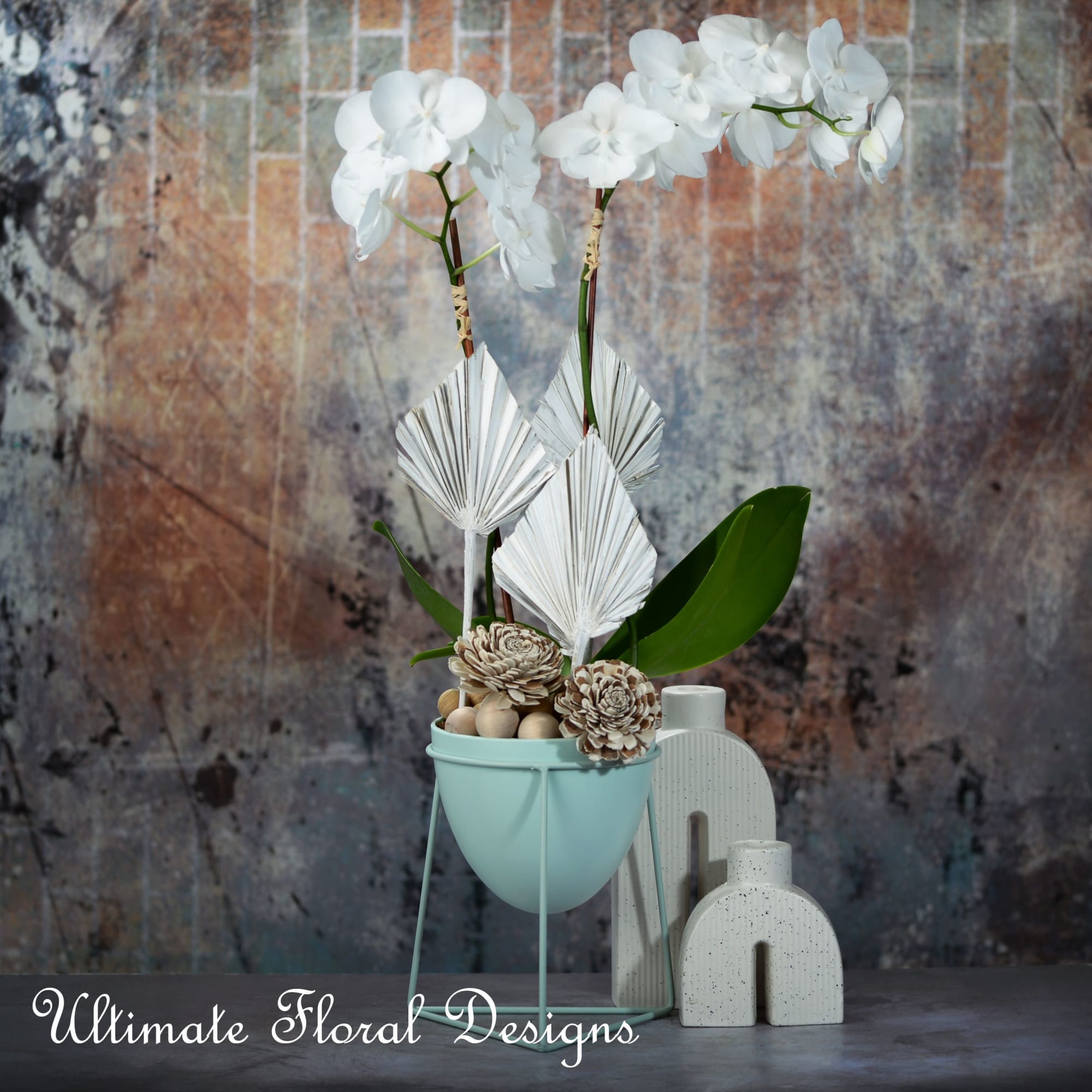 White orchids in a mint pot with decorative accents