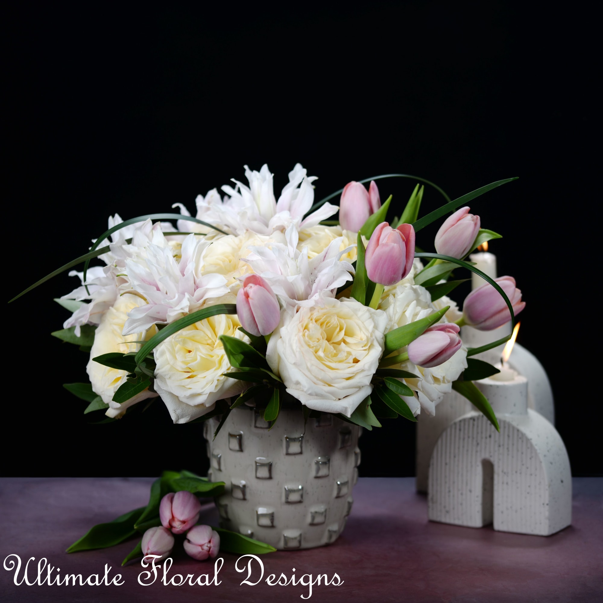 White roses and pink tulips arranged in a textured ceramic vase