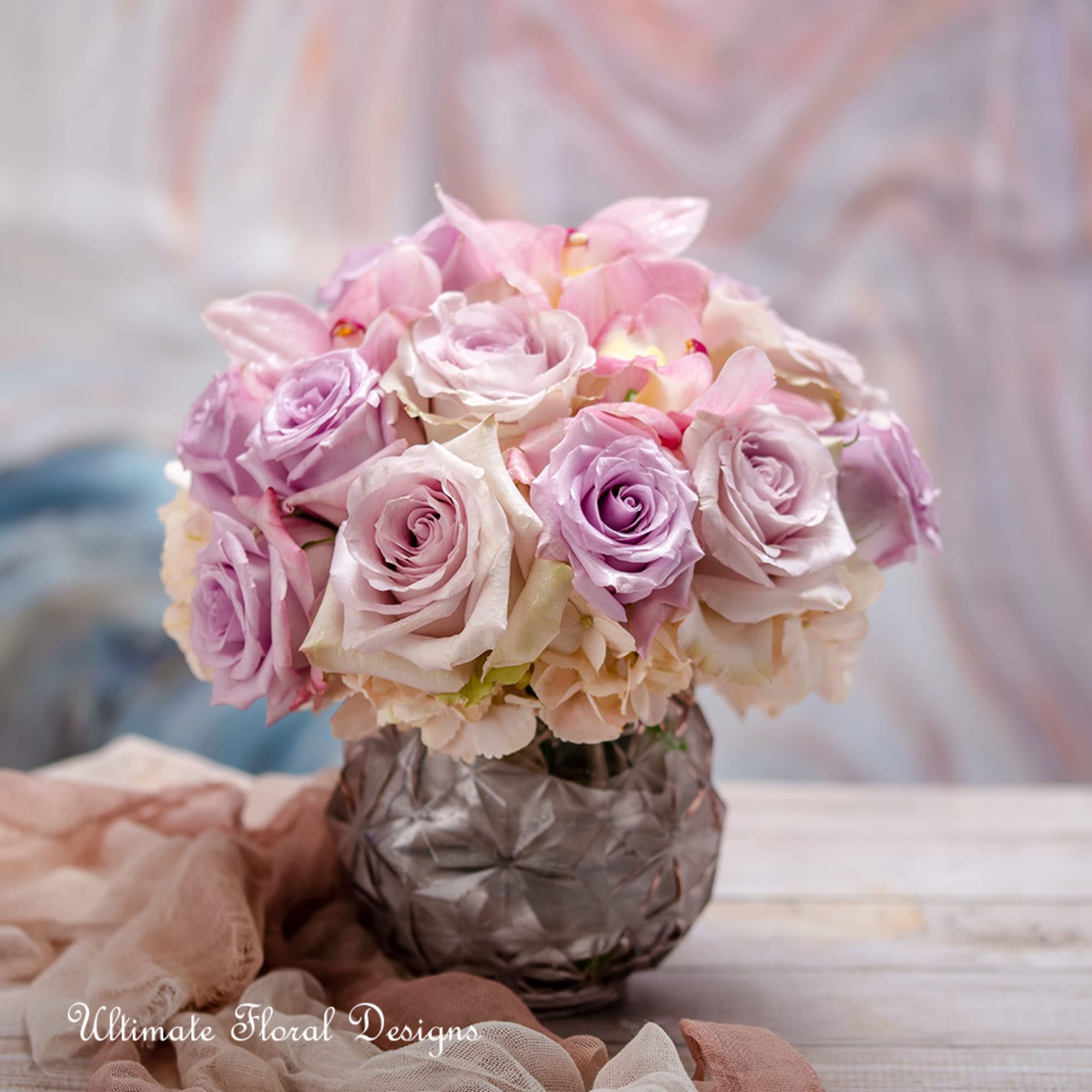 Pink and lavender roses arranged in a small glass vase