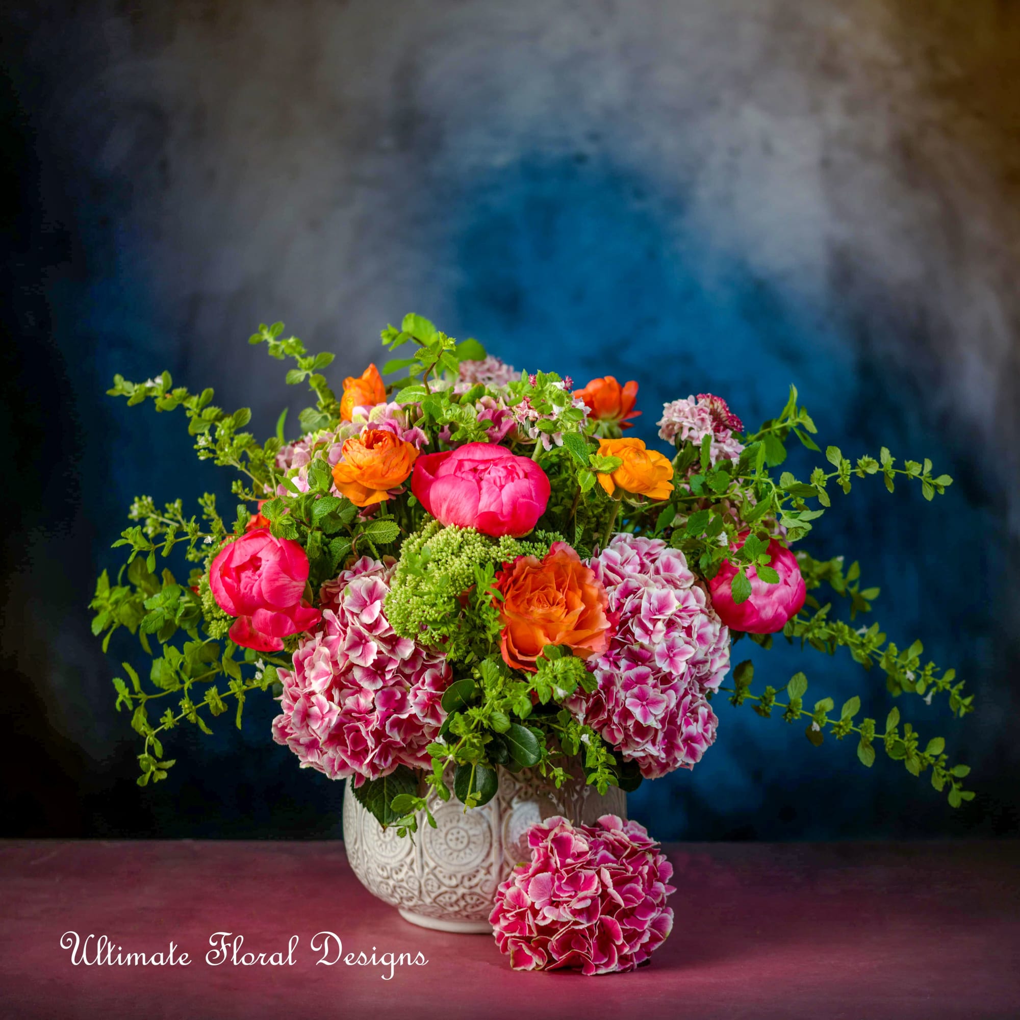 Bright mixed bouquet in a white patterned vase with pink and orange blooms