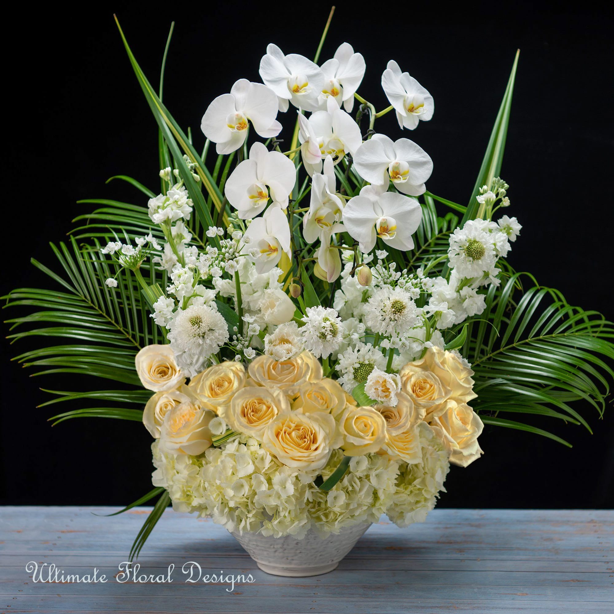 White orchids and cream roses in a low white vase
