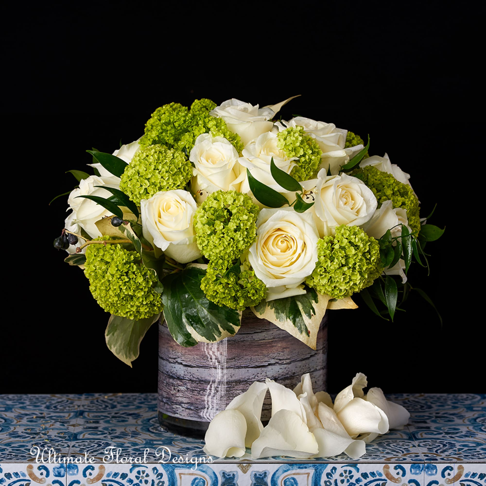 White roses and green hydrangea in a rustic vase with white calla lilies below