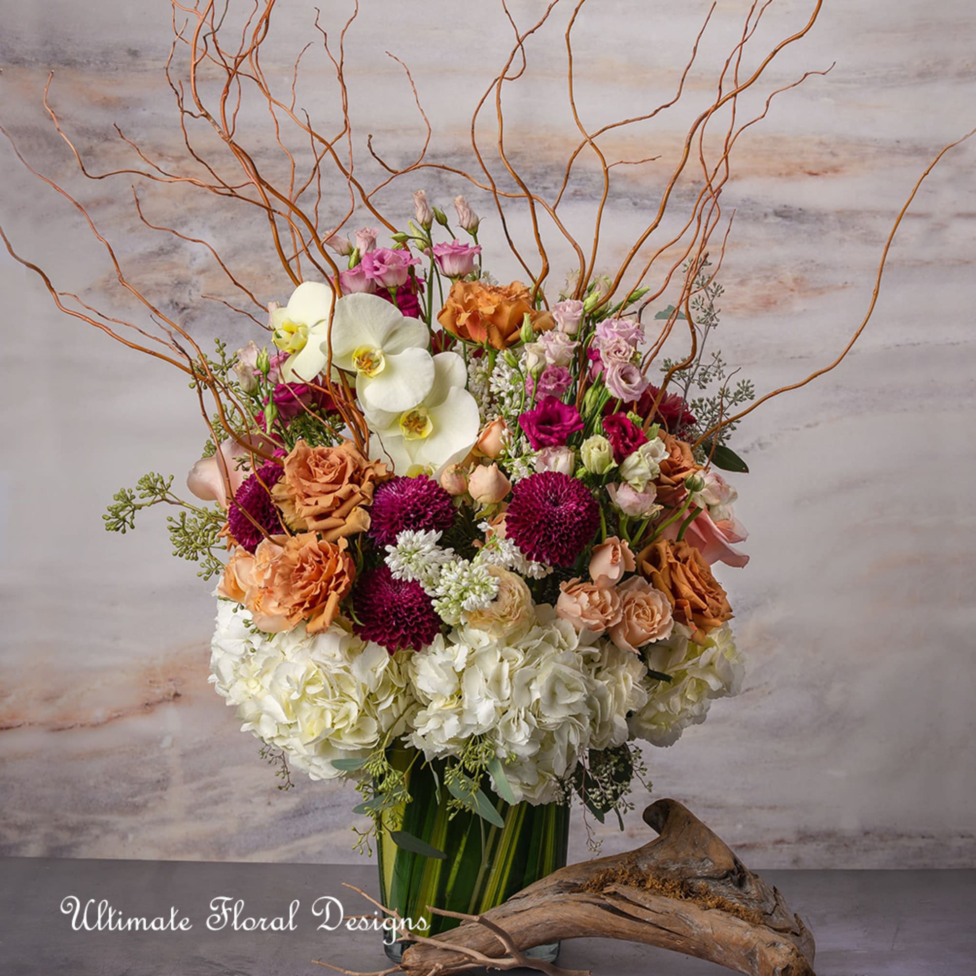 Tall floral arrangement with orchids, roses, hydrangeas, and decorative branches