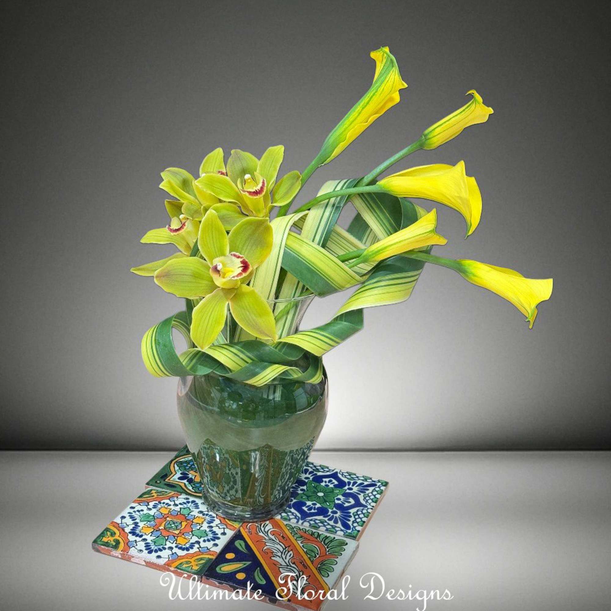 Yellow-green orchids in a glass vase on patterned tiles
