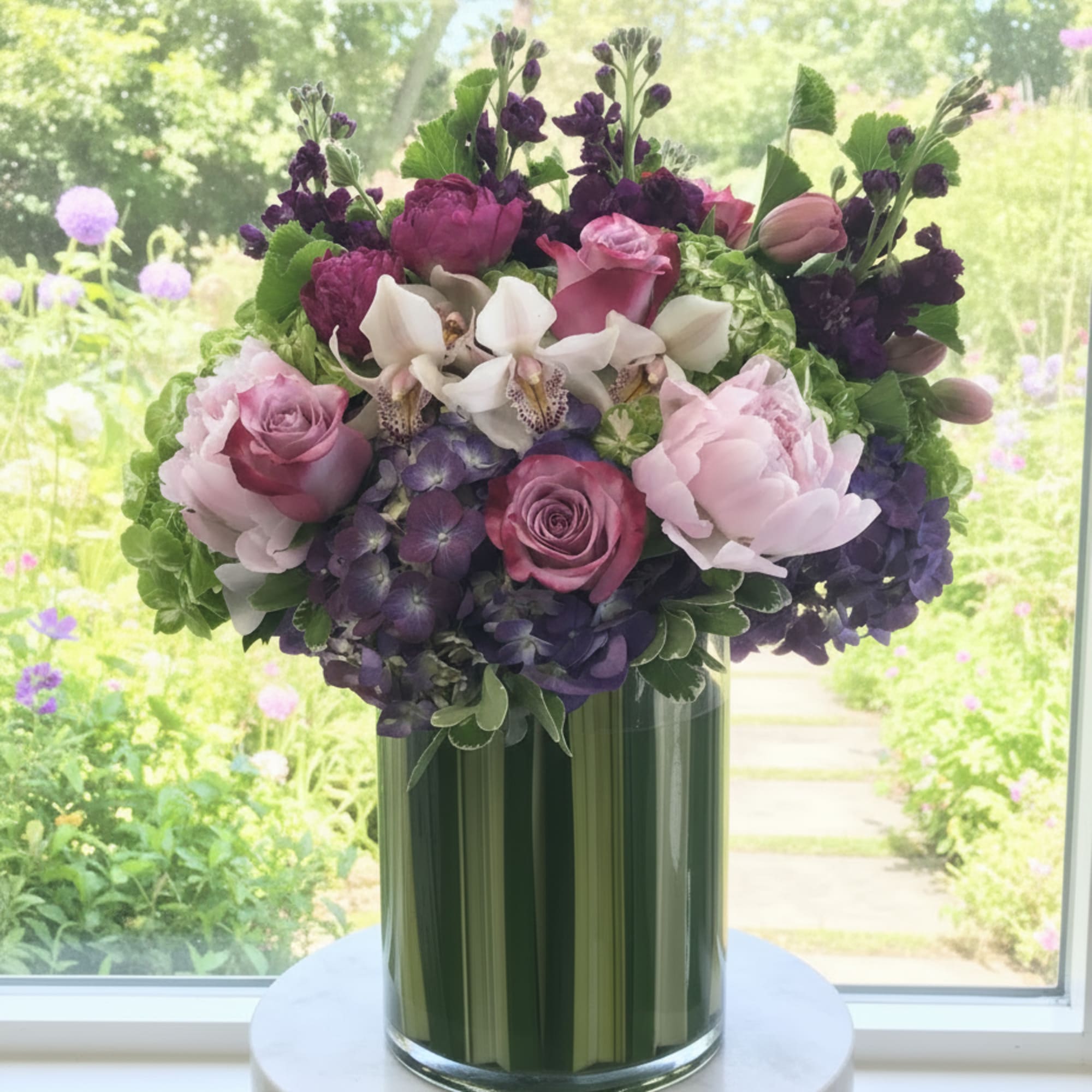 Bouquet of pink, purple, and white flowers in a tall glass vase