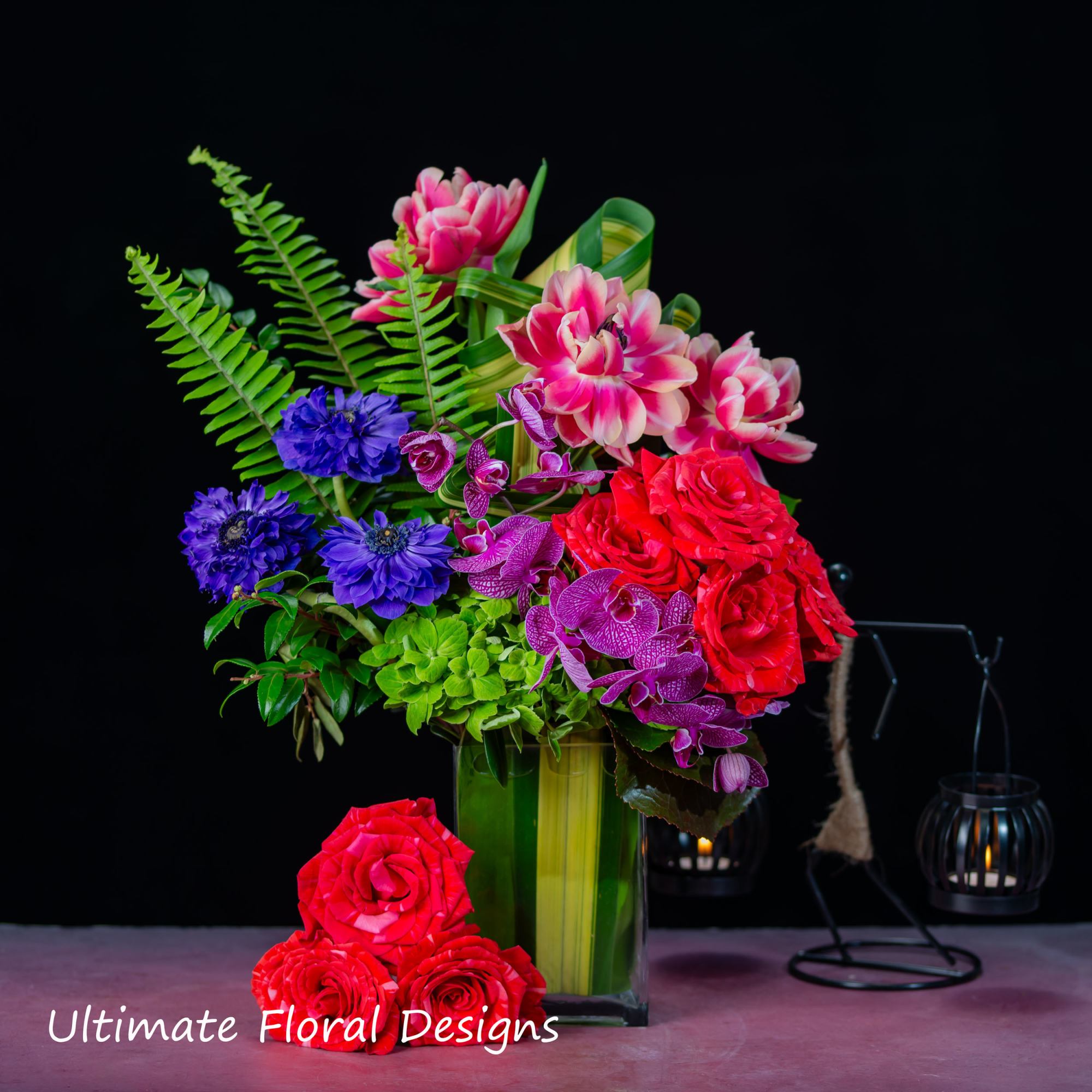 Colorful floral arrangement in a tall green vase with roses and orchids