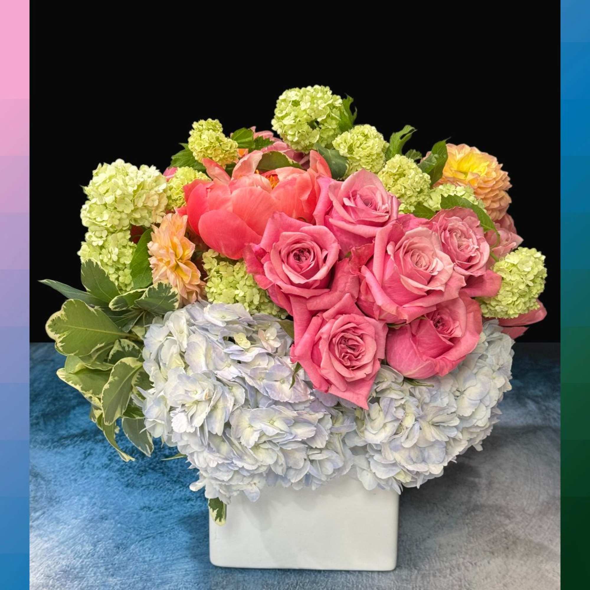 Pink roses and hydrangeas arranged in a white square vase