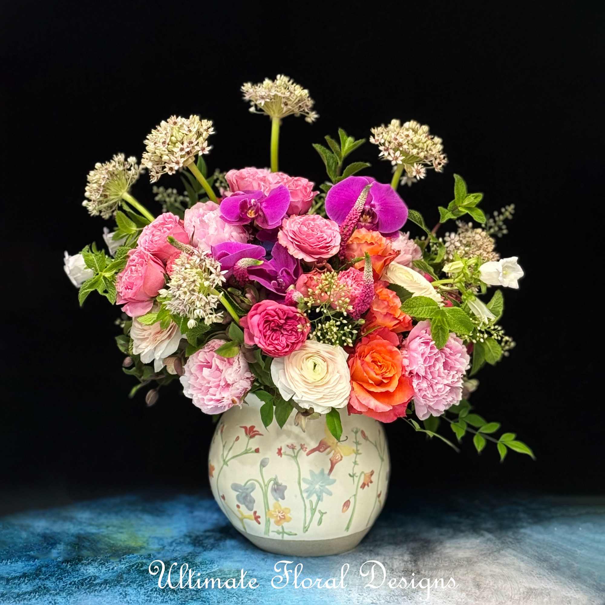 Mixed pink and purple flowers arranged in a painted ceramic vase