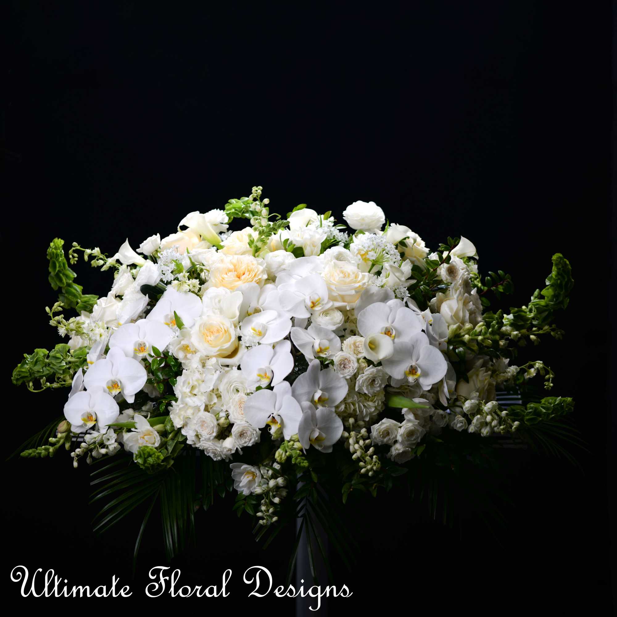Large white floral arrangement with orchids and roses on a black background