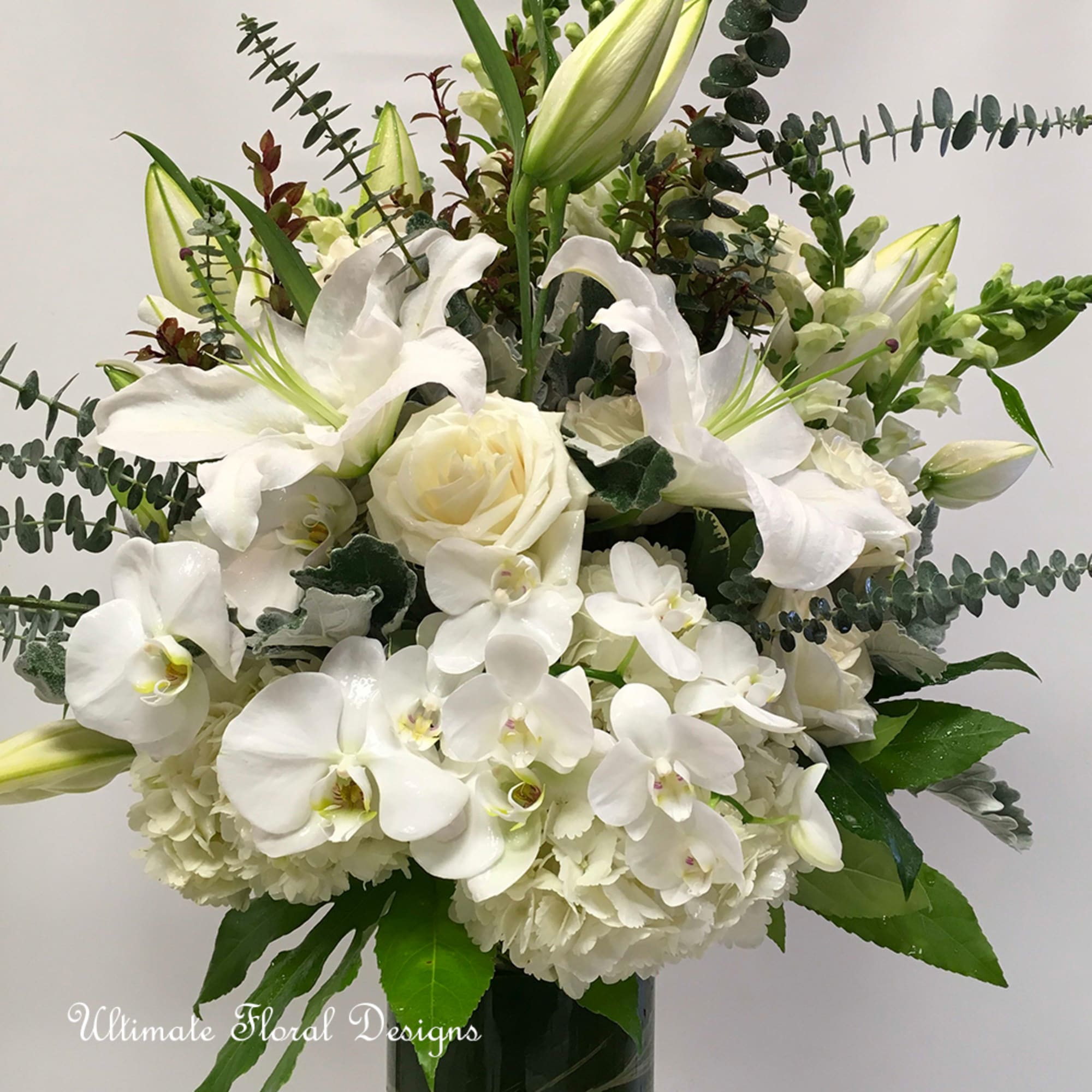 White lilies, roses, and orchids arranged in a vase