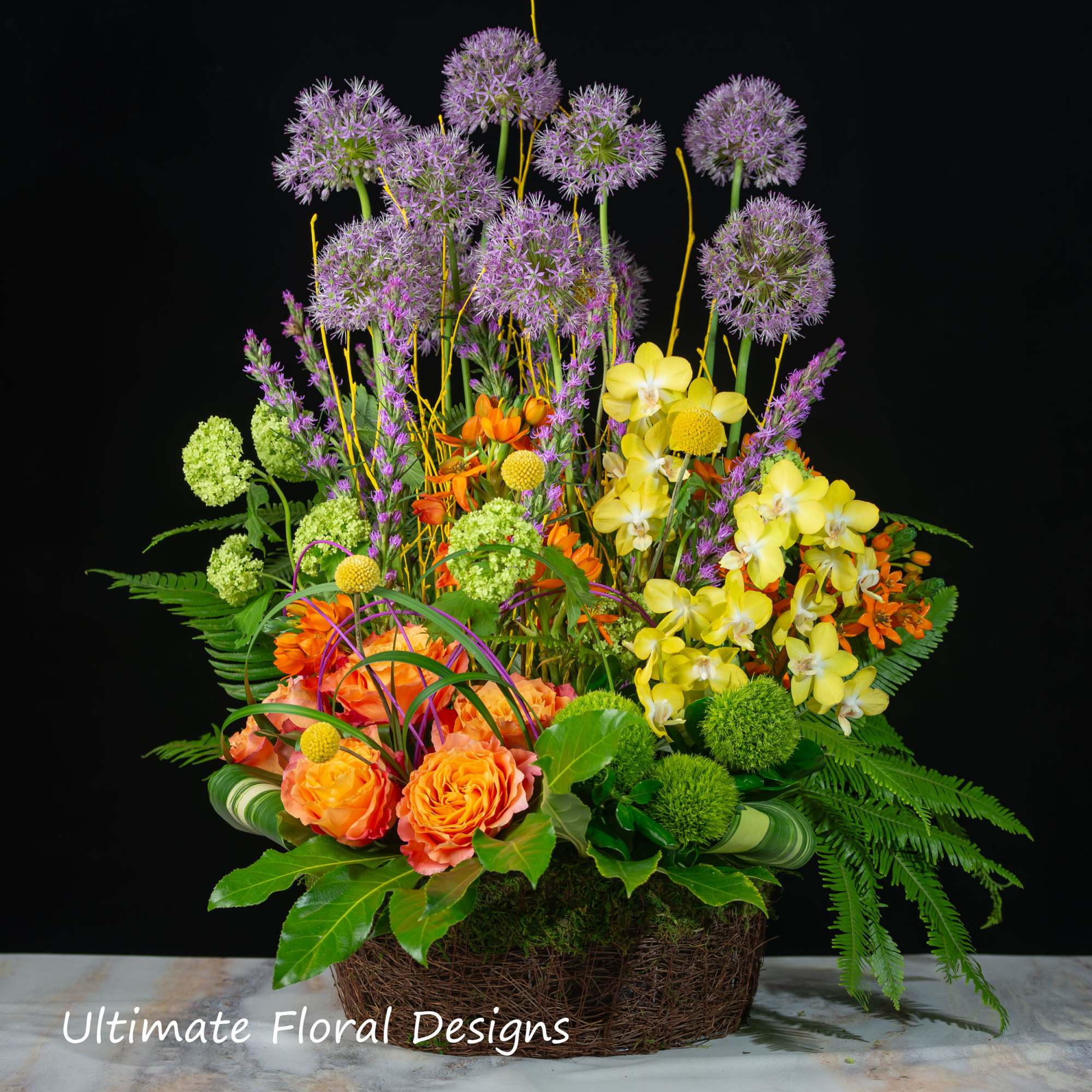 Colorful floral arrangement in a woven basket with tall purple blooms and orange roses