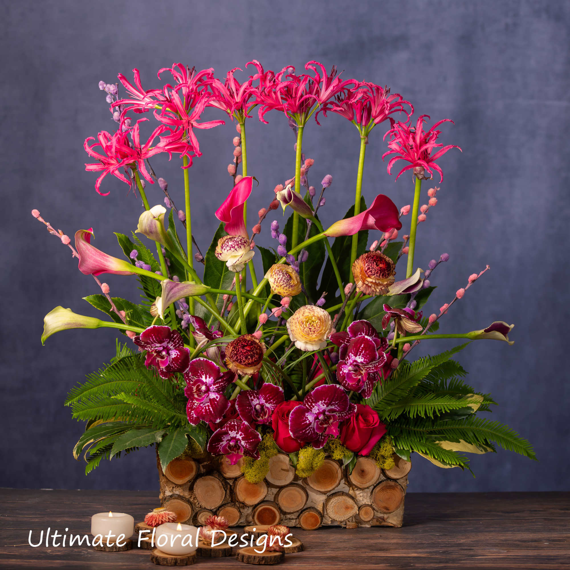 Tall floral arrangement with pink lilies, orchids, and calla lilies in a log container