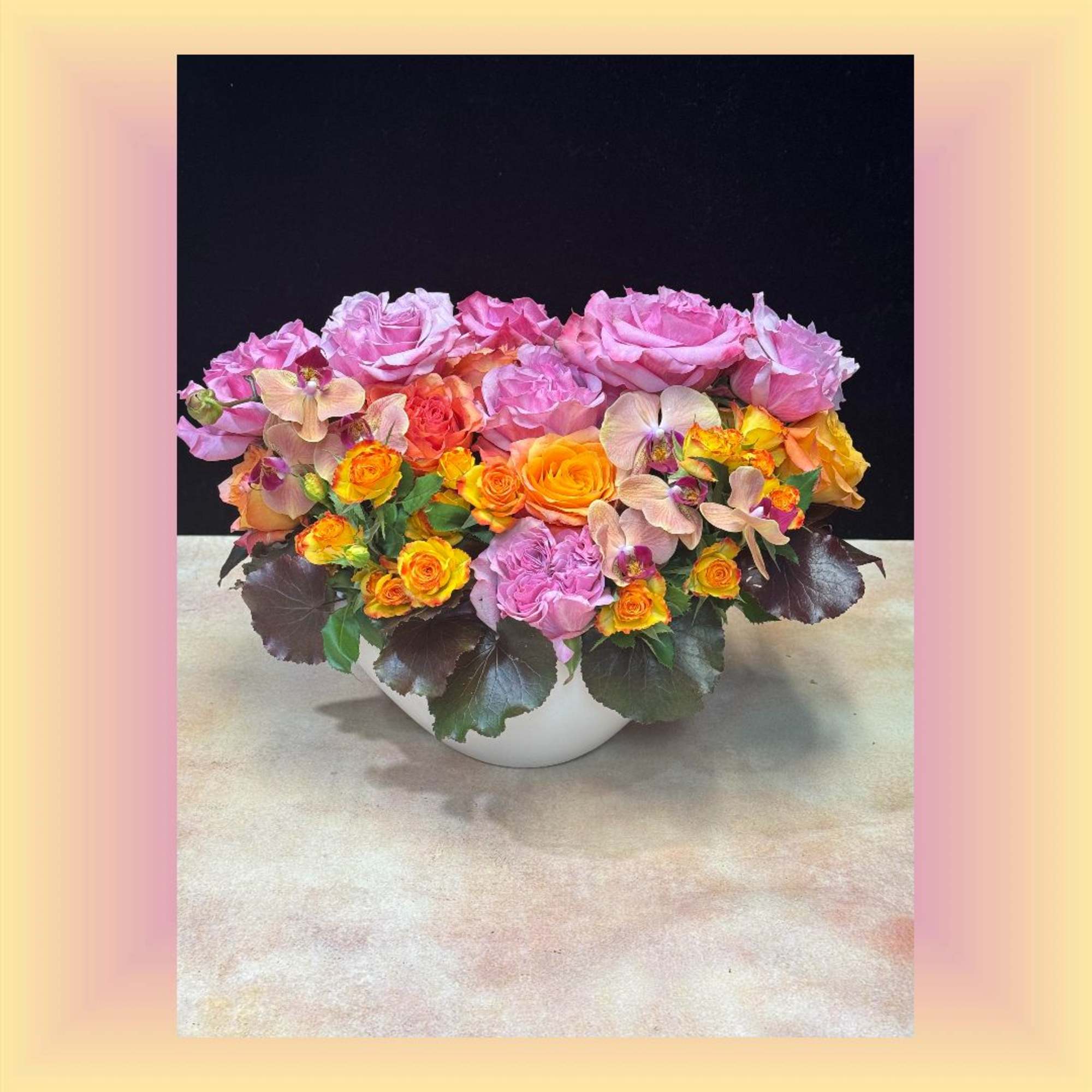 Pink and orange roses arranged in a white bowl vase