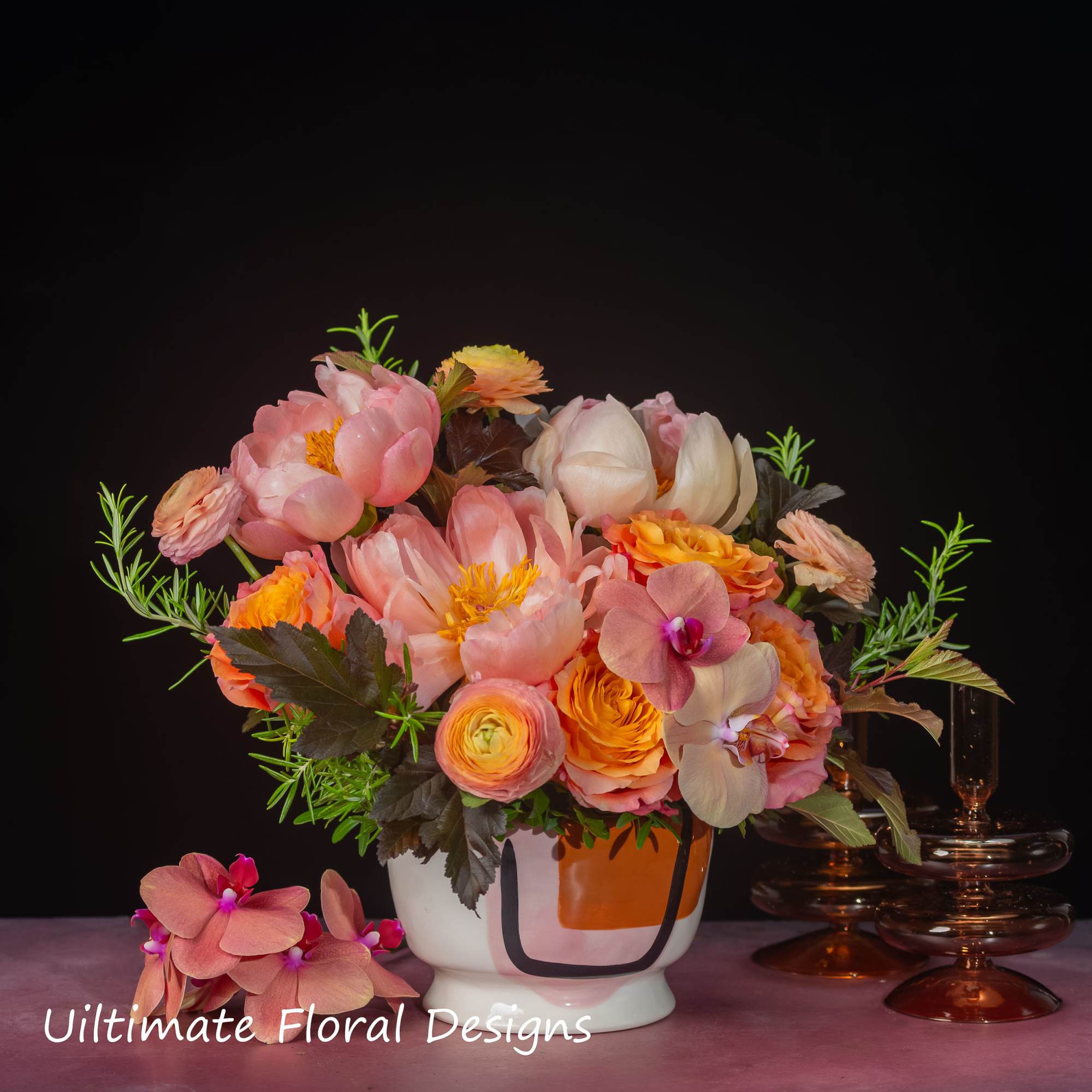 Pink and peach floral arrangement in a white vase with orchids