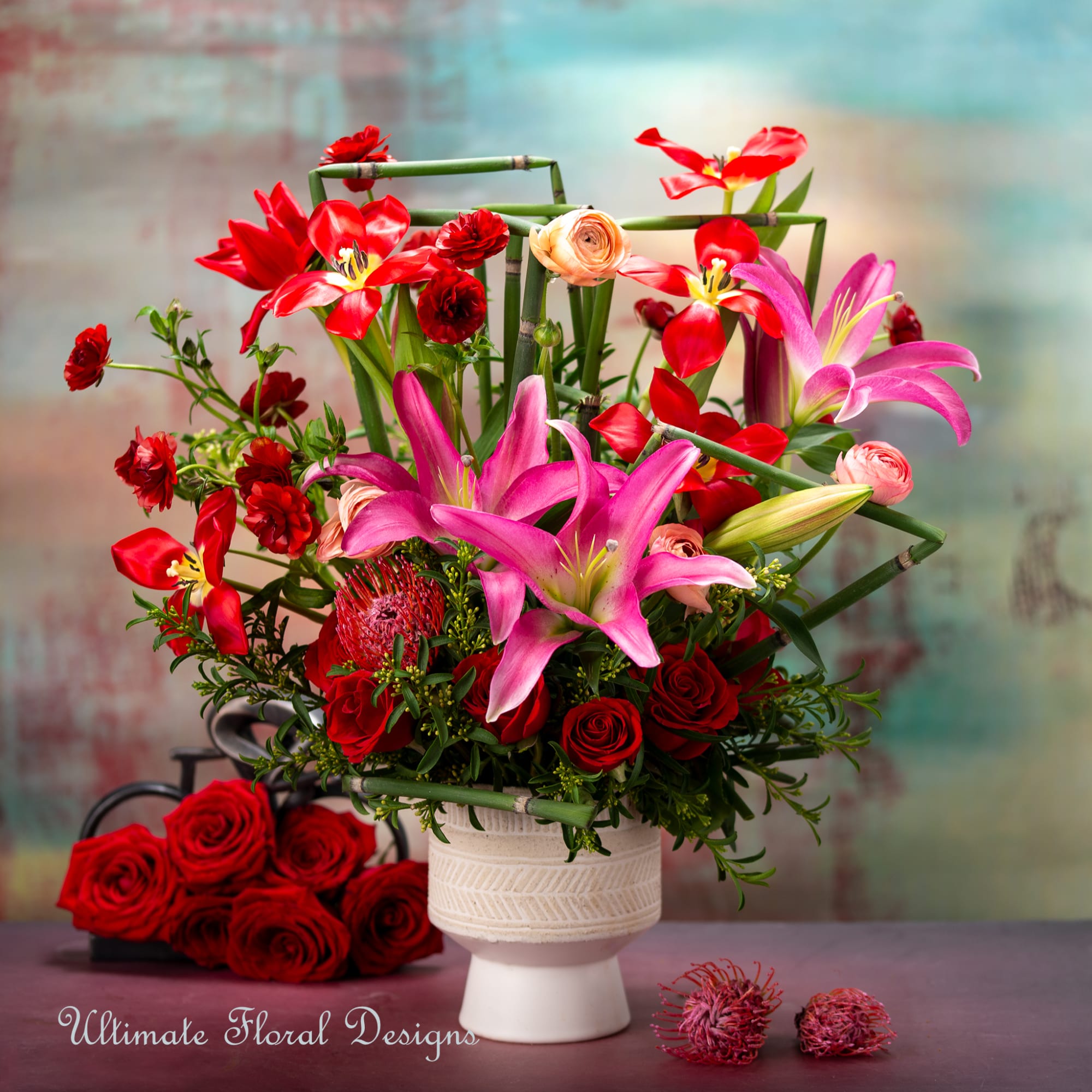 Pink lilies and red roses in a white vase with bamboo accents