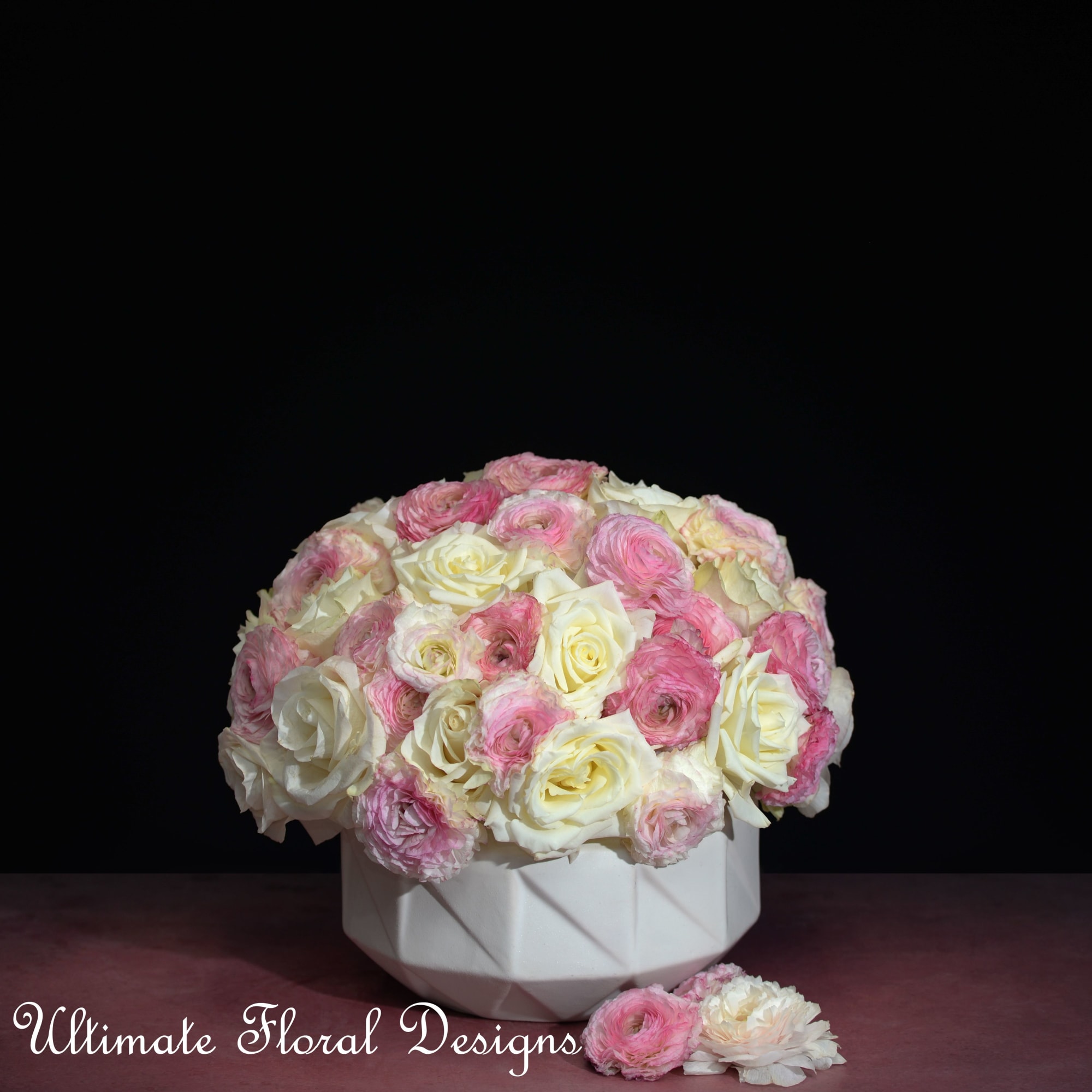 Pink and white rose arrangement in a white geometric vase