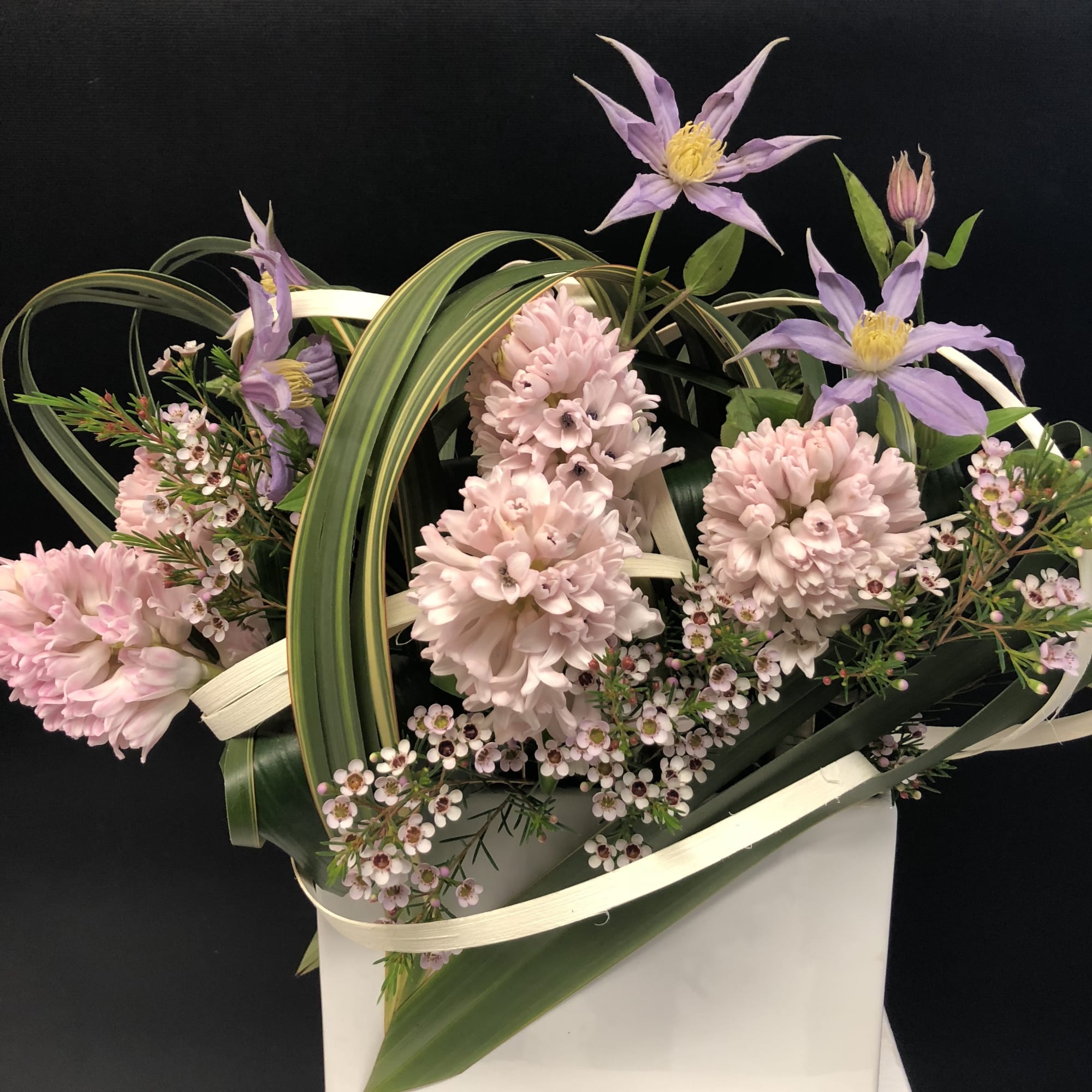Pink and lavender flowers arranged in a white gift bag