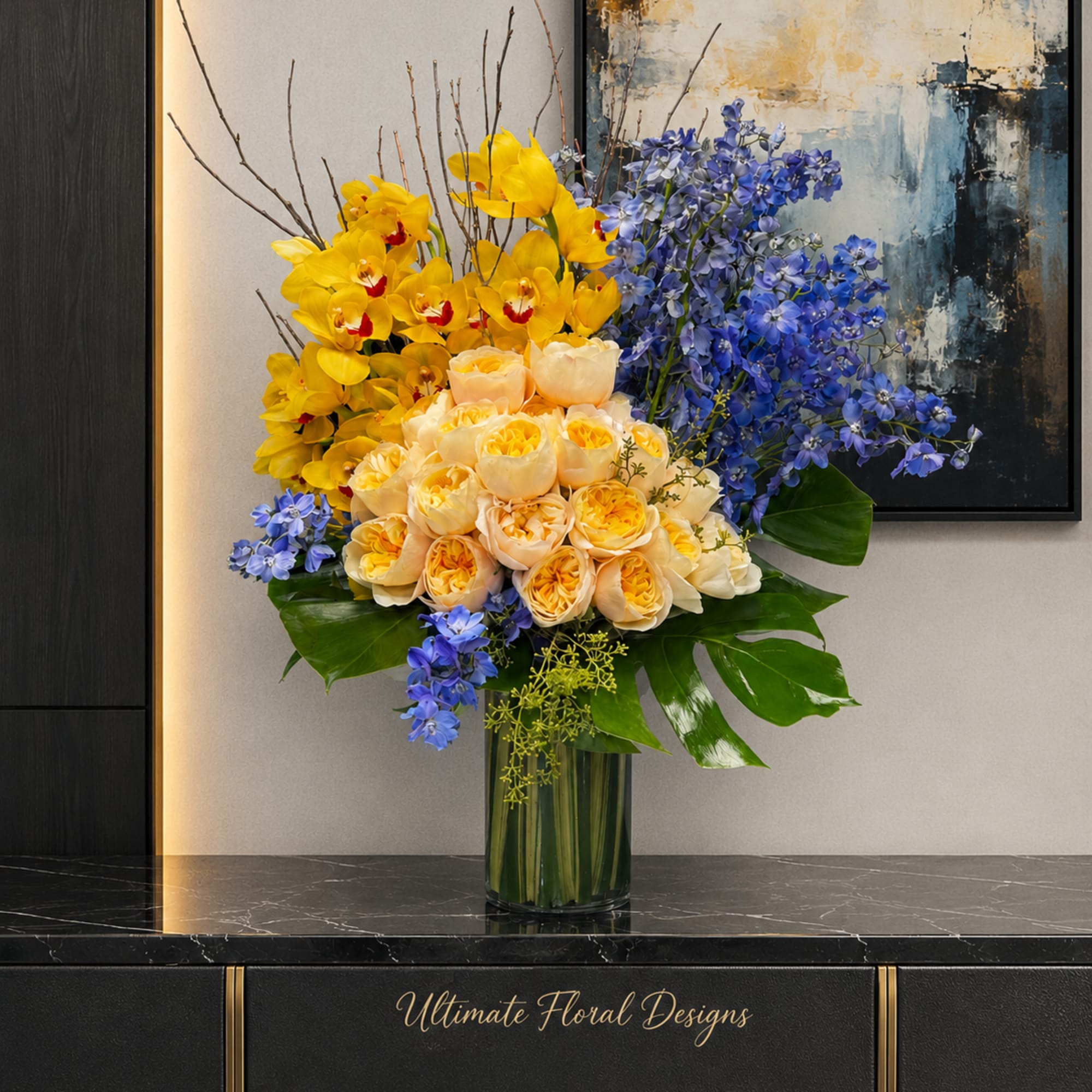 Yellow and peach roses with blue flowers in a glass vase