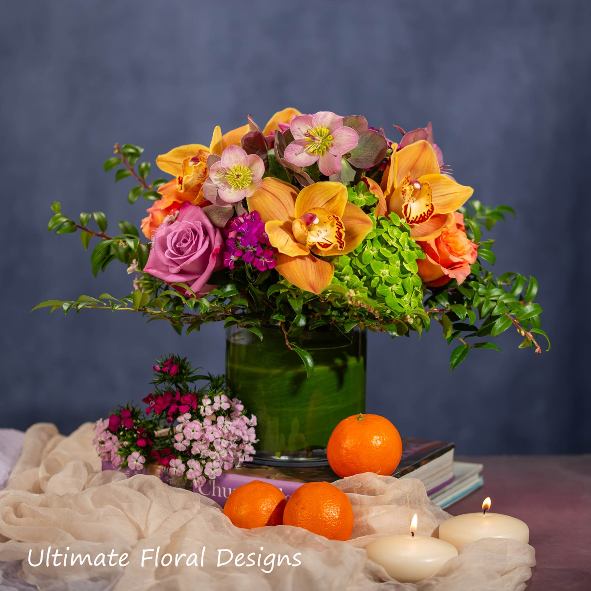 Mixed floral arrangement in a green vase with oranges and candles