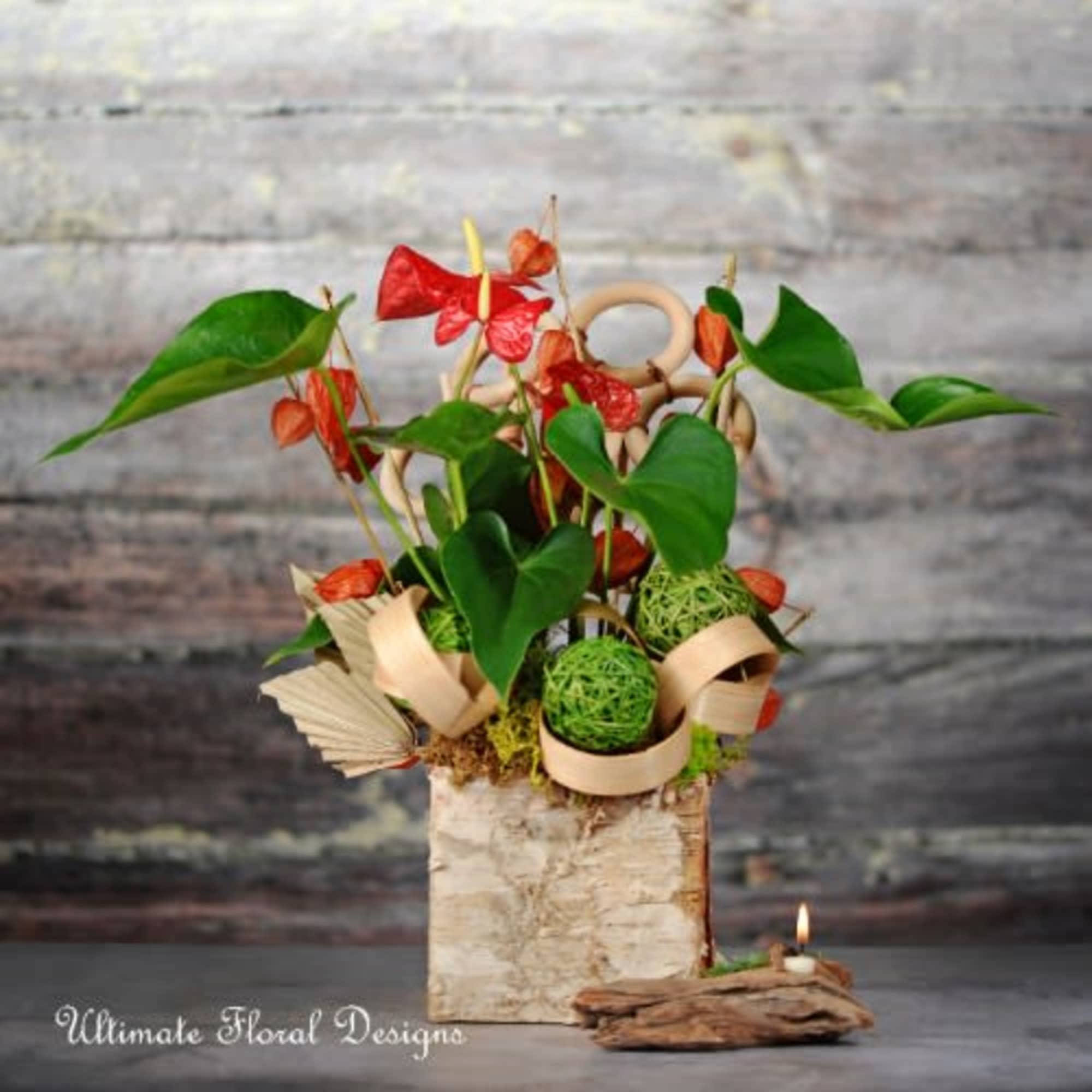 Tropical floral arrangement with red blooms in a birch-style container